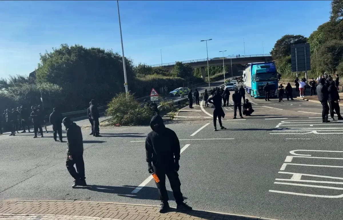 Dozens of balaclava-wearing protesters stand in the road