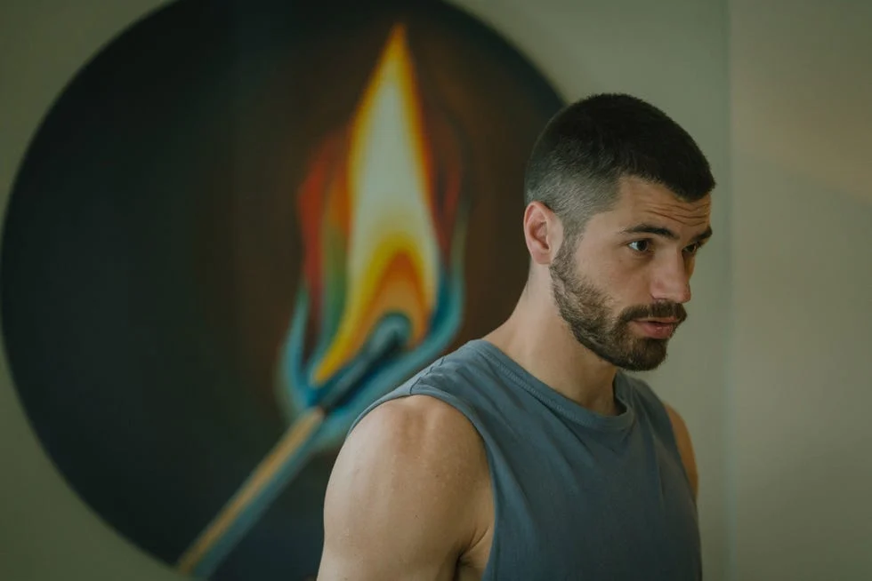 person standing in front of a colorful flame painting