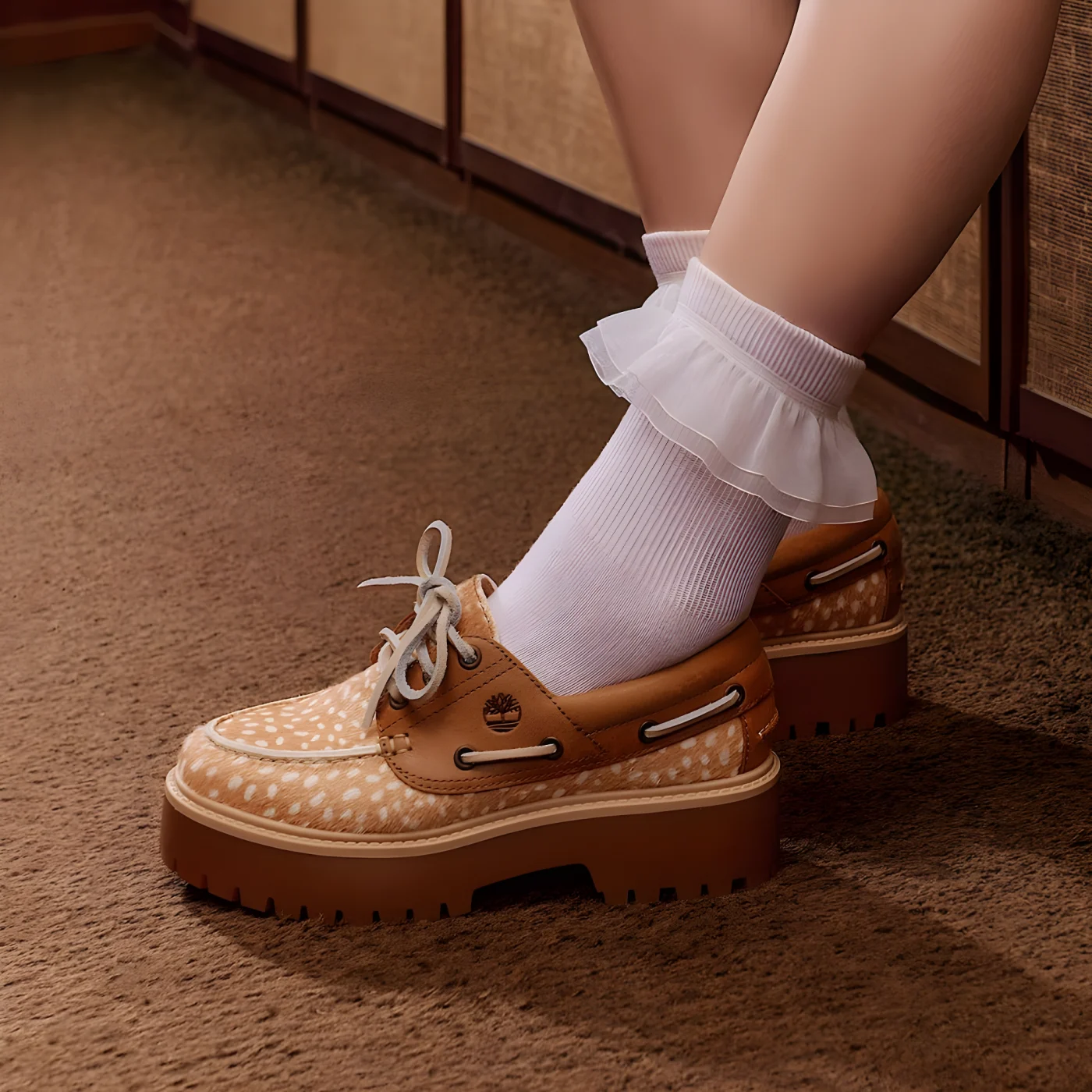 person wearing white ruffled socks and tan boat shoes with polka dots on brown carpet.