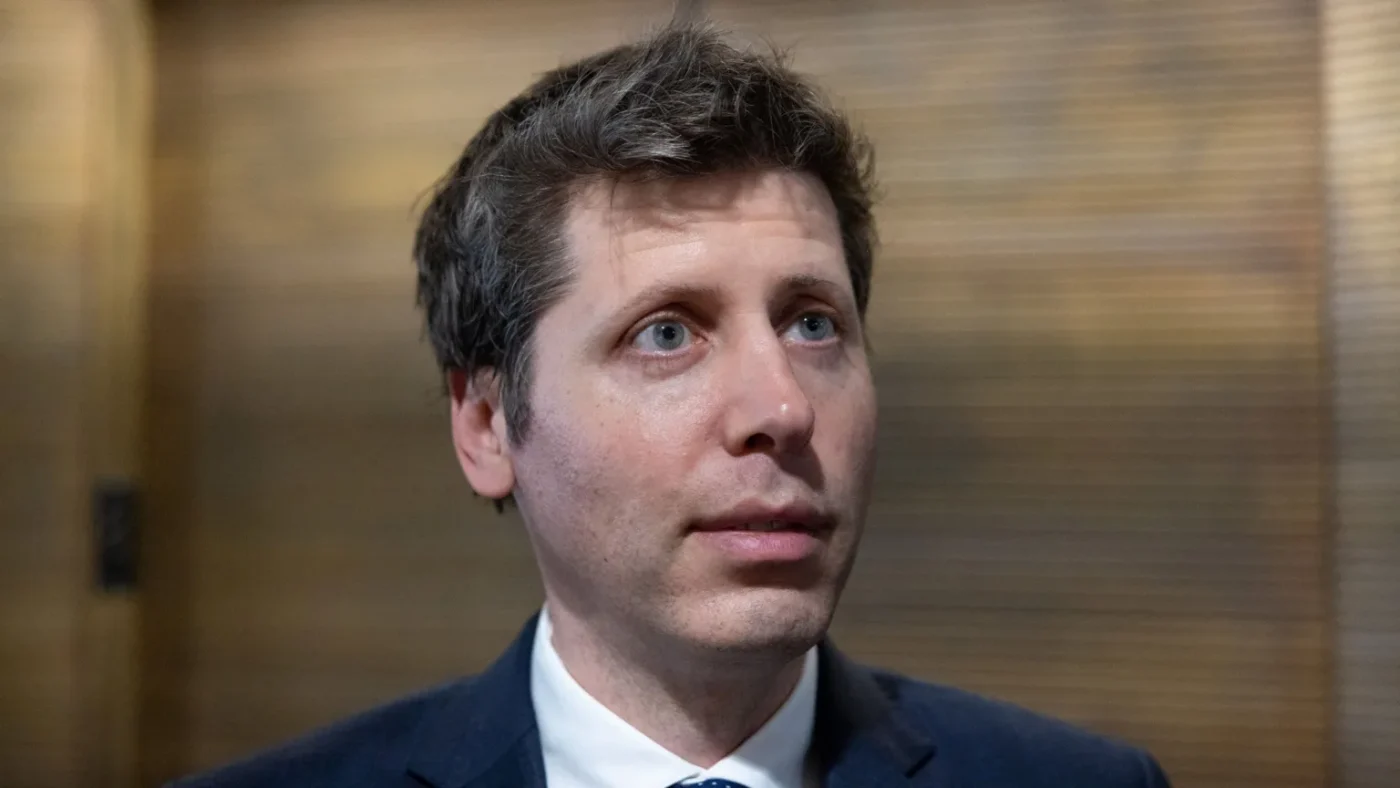 Reuters OpenAI CEO Sam Altman standing before a lobby of elevators answering questions from reporters.