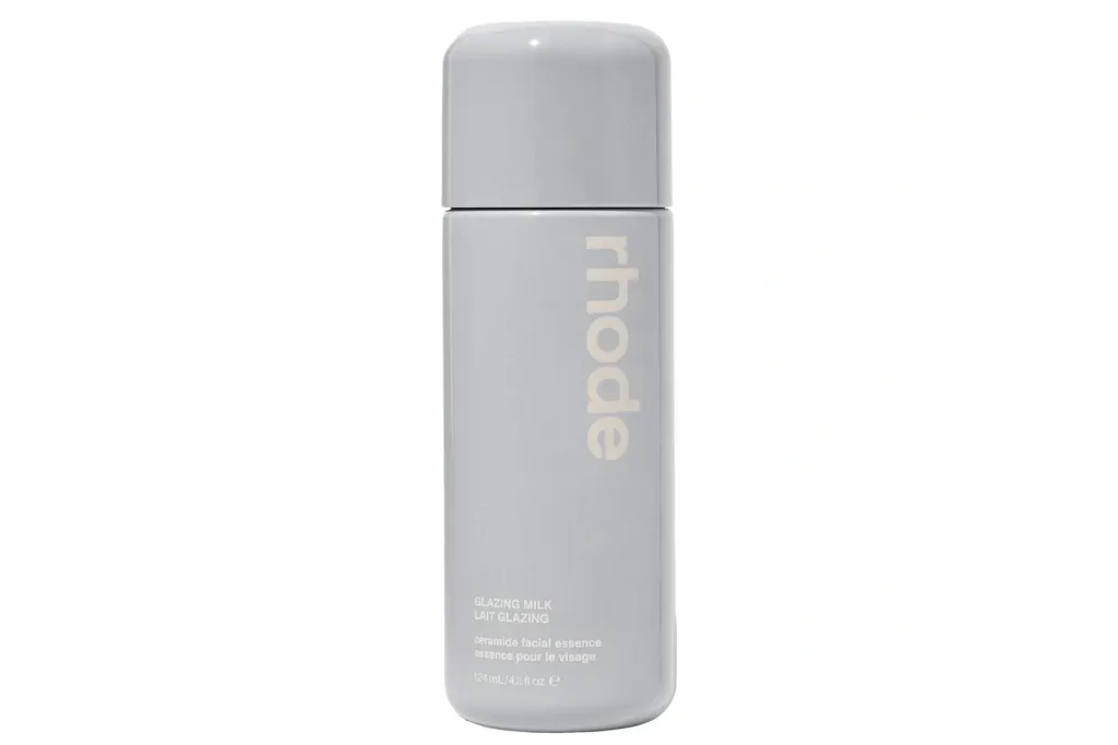 A bottle of Rhode Glazing Milk ceramide facial essence in a light grey container.