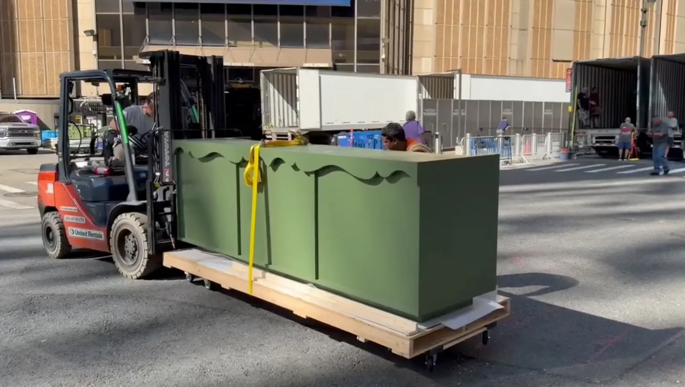 A forklift moving a large green cabinet outside Madison Square Garden.