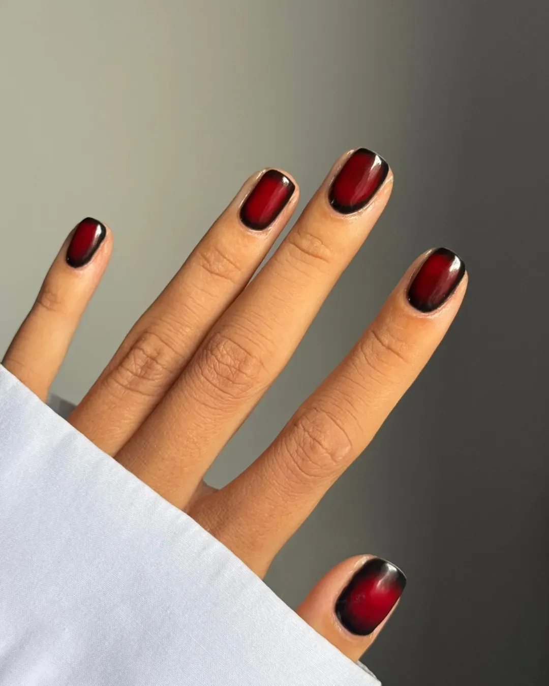 A hand featuring manicure with dark nail polish