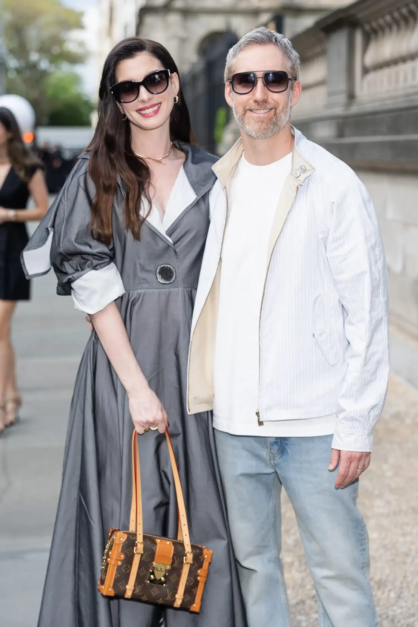 A man and a woman posing together outdoors she is holding a handbag