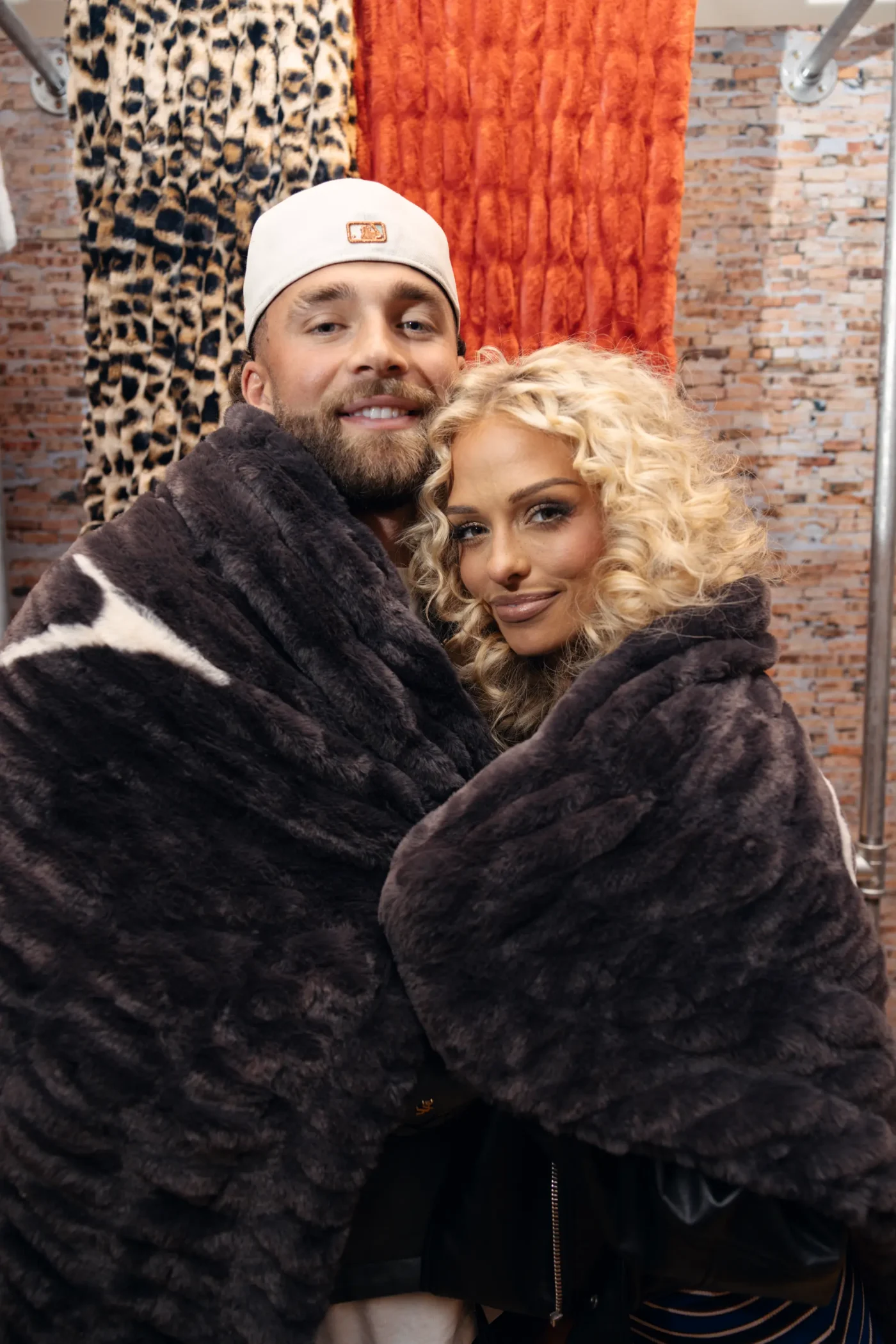 A man and a woman wrap themselves in plush dark grey blankets inside the Minky Couture pop-up shop.