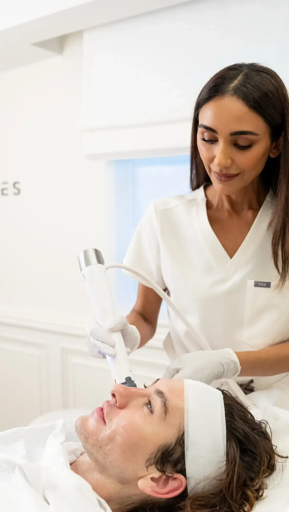 A medical aesthetician performs a skin-tightening procedure on a client