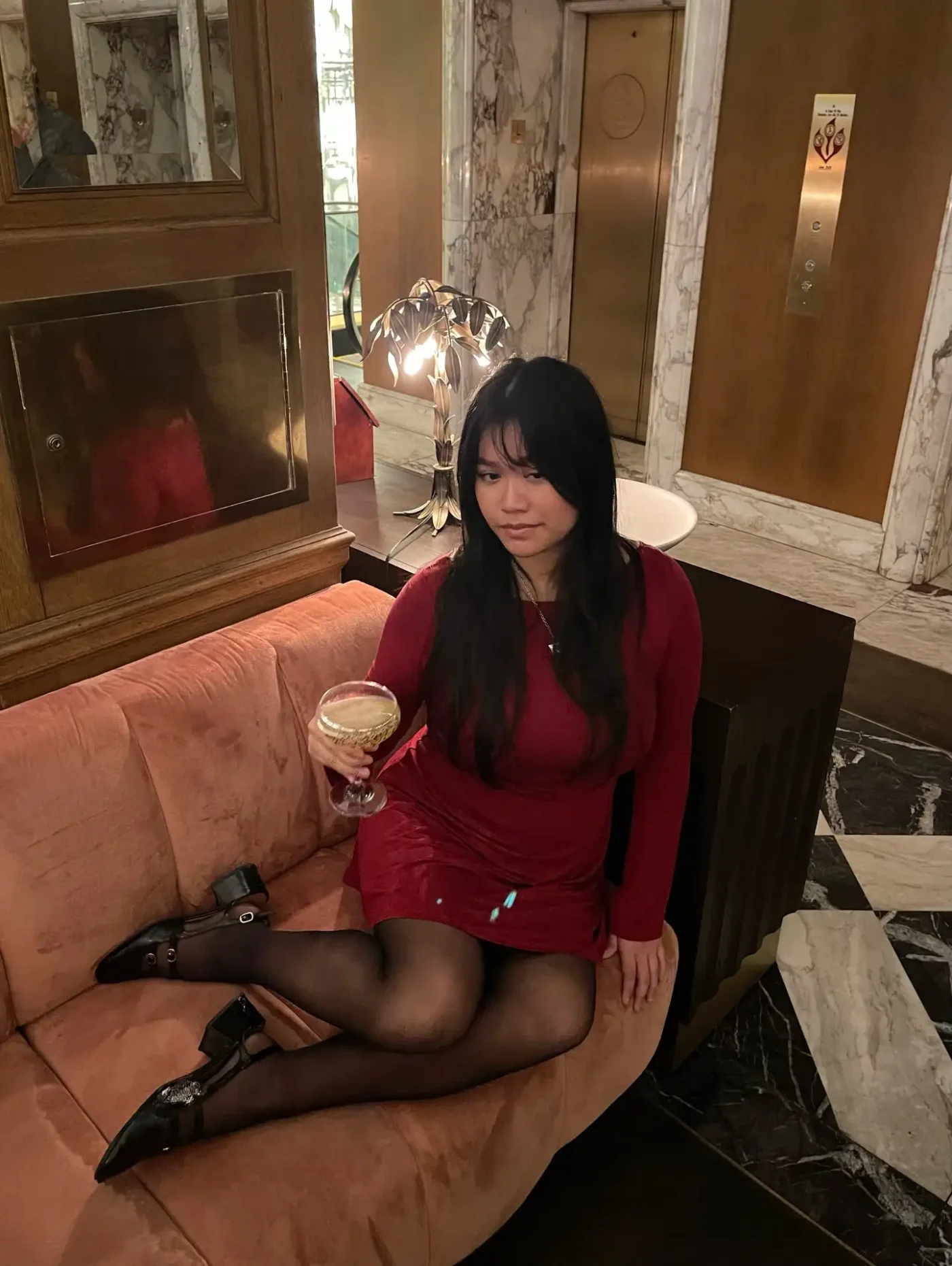 A person sitting on a sofa holding a drink in an elegant interior setting