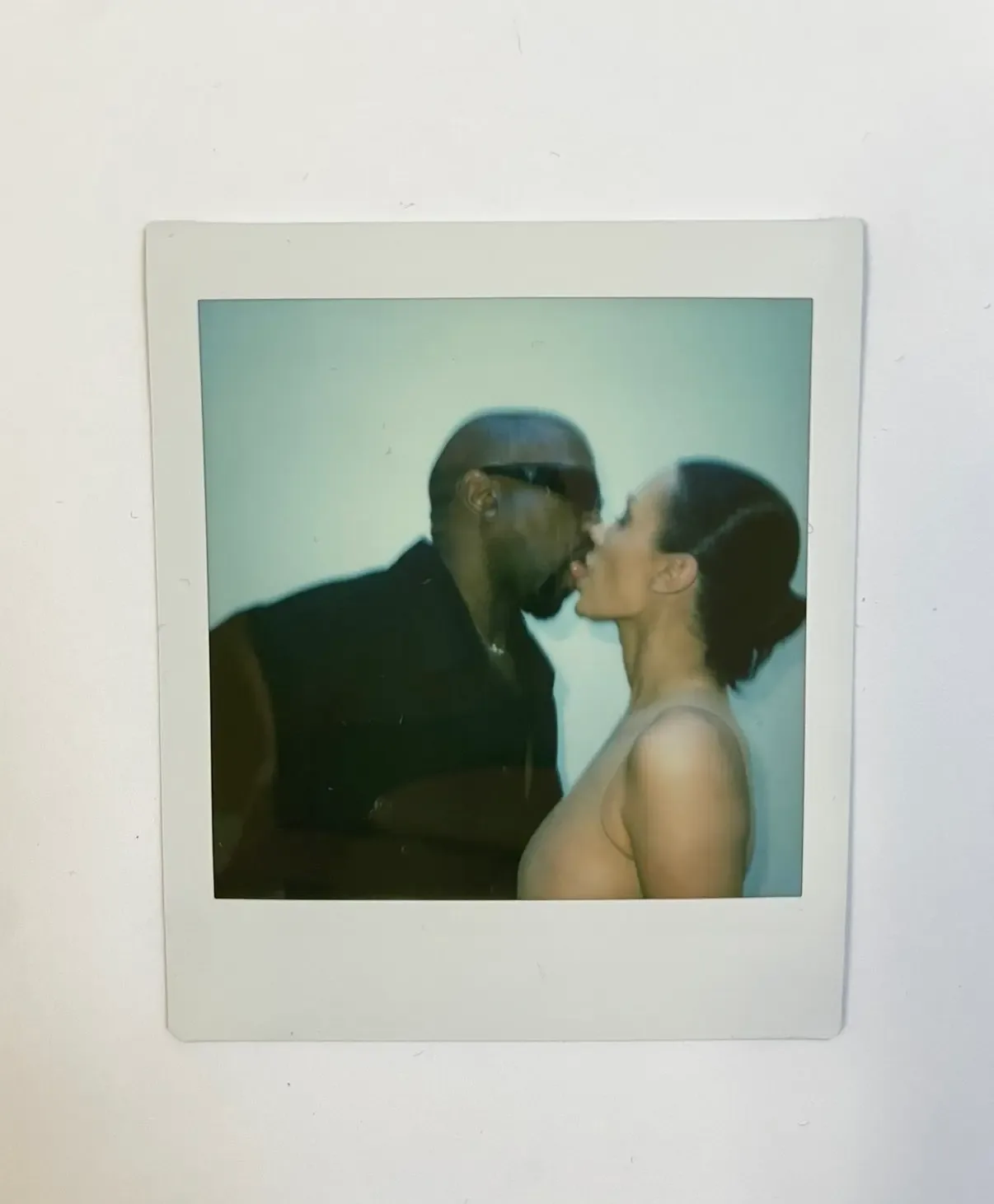 A Polaroid photograph of Kanye West and Bianca Censori sharing a kiss.
