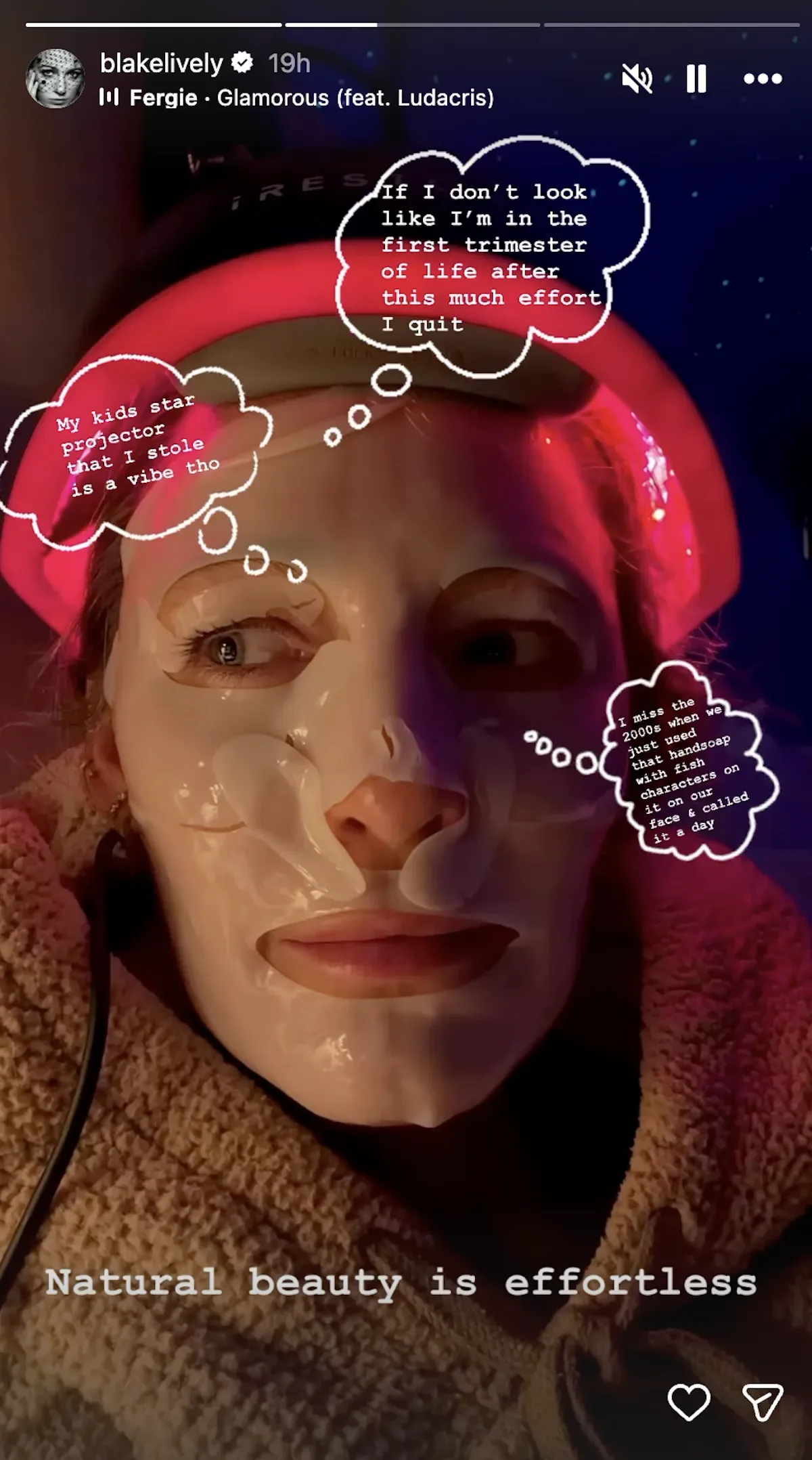 A selfie of Blake Lively wearing an LED skin therapy mask on her head and several targeted, peel-off face masks. She is wearing a fuzzy robe and there are several bubbles of text on the screen.
