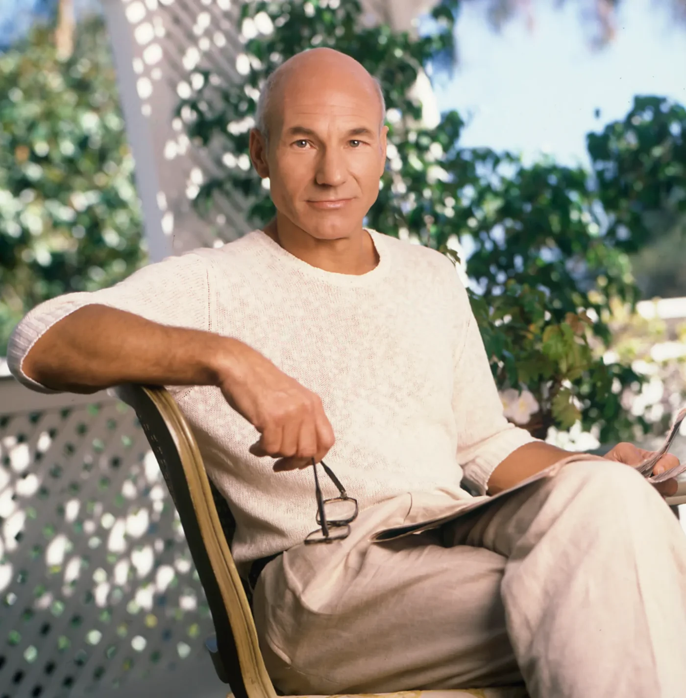 Actor Patrick Stewart poses for a portrait sitting in a chair outdoors.