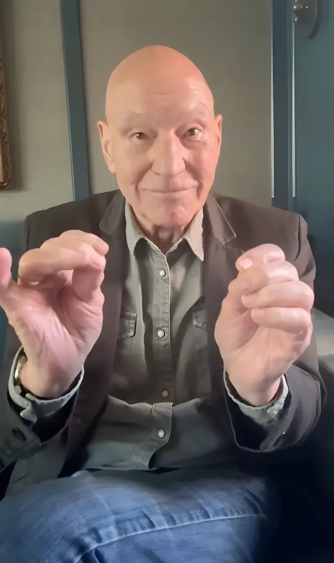 Actor Patrick Stewart smiling while gesturing with his hands.