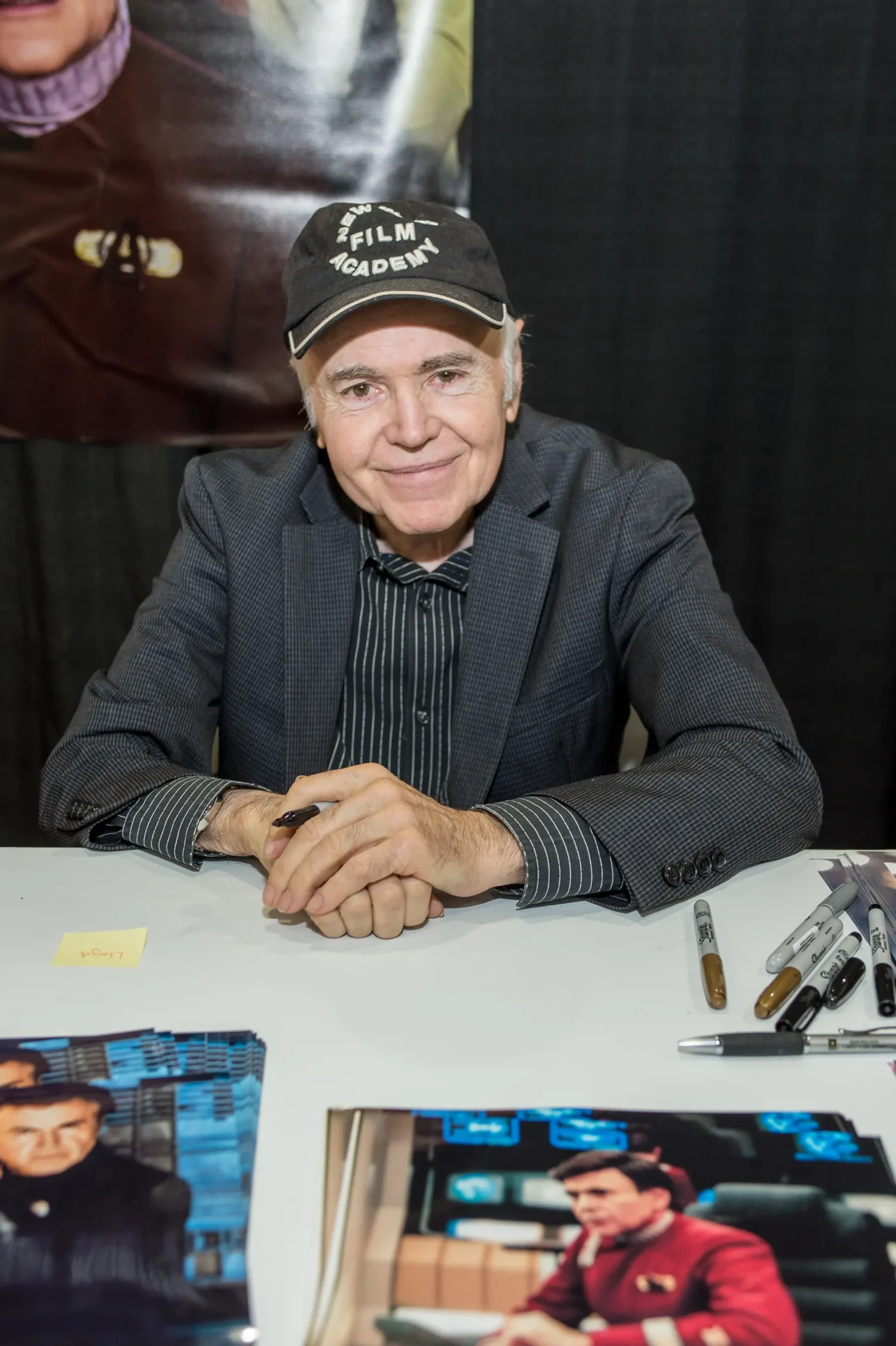 Actor Walter Koenig sits behind a table at an autograph signing event.