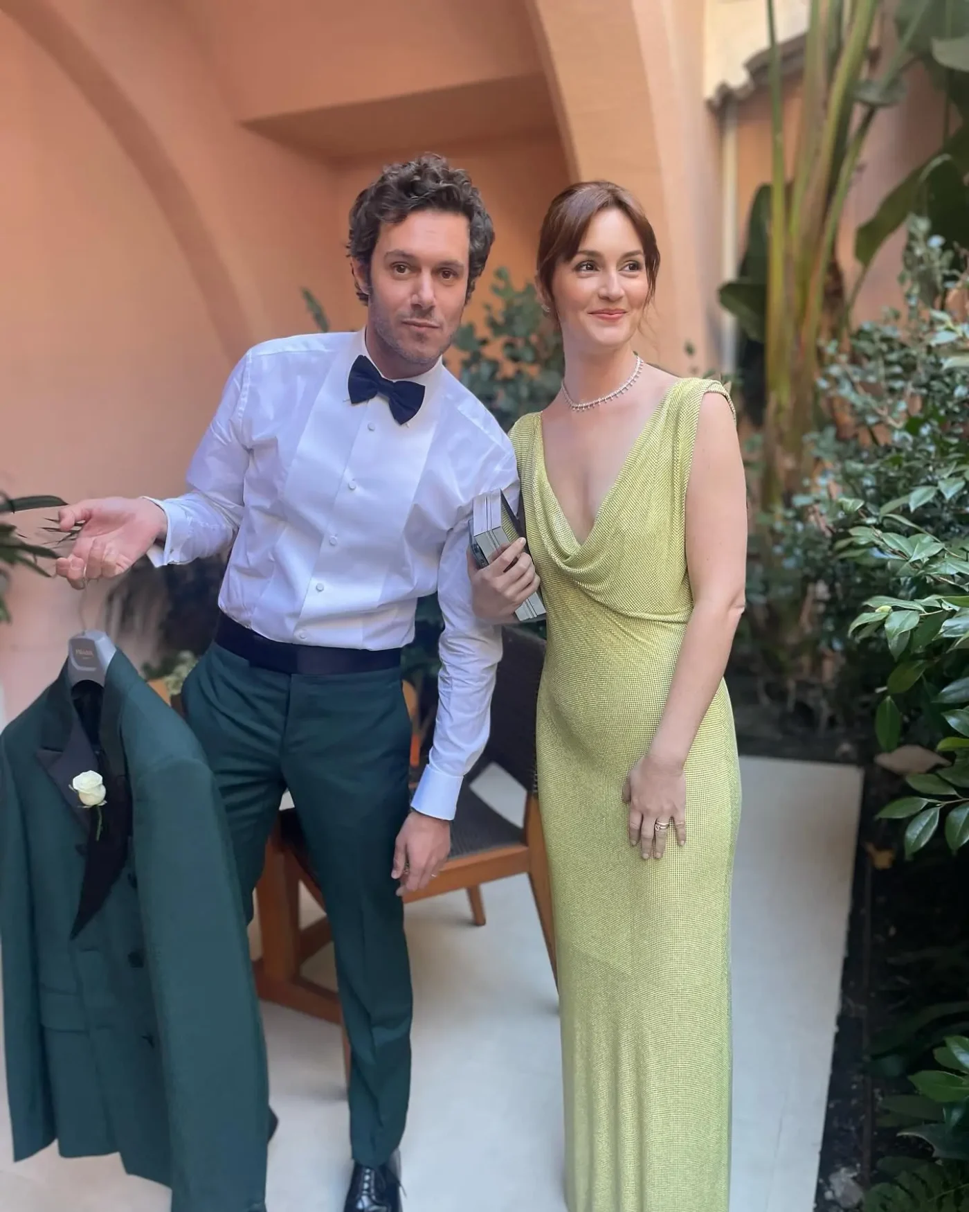 Adam Brody holding a green suit jacket and Leighton Meester wearing a yellow dress.