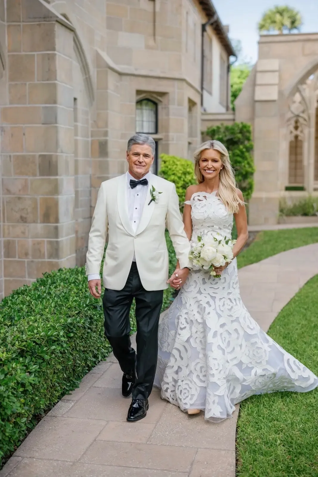 Ainsley Earhardt and Sean Hannity holding hands and walking together outside on their wedding day.