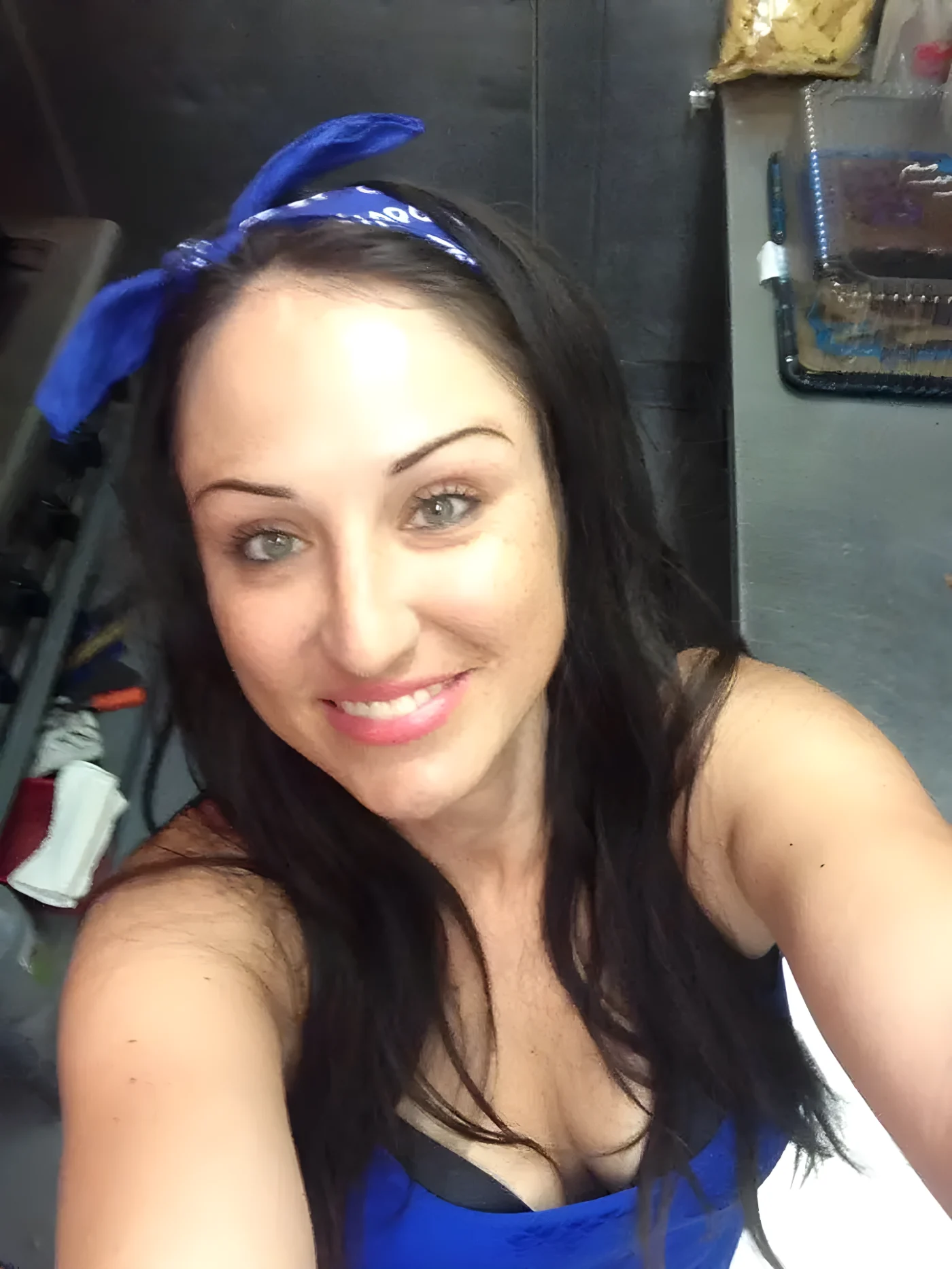 Amber Siyavus smiles at the camera, wearing a blue bandana in her hair.