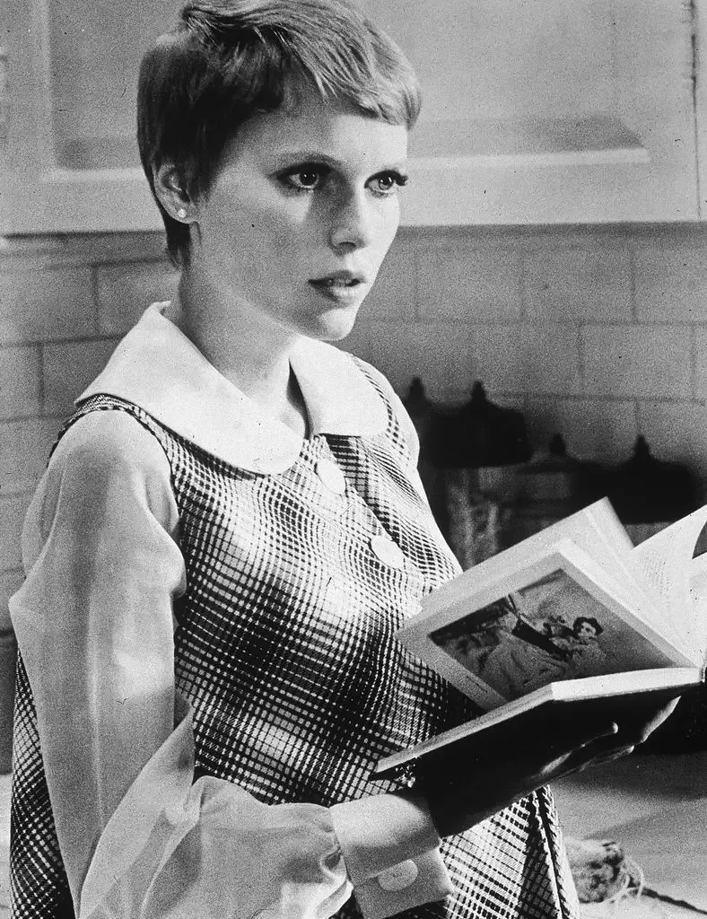 American actor Mia Farrow holds a book in a still from the film, 'Rosemary's Baby,' directed by Roman Polanski, 1968