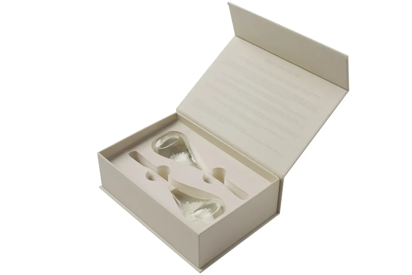 An open beige gift box containing two glass cryo globes and a care guide on the inside lid.