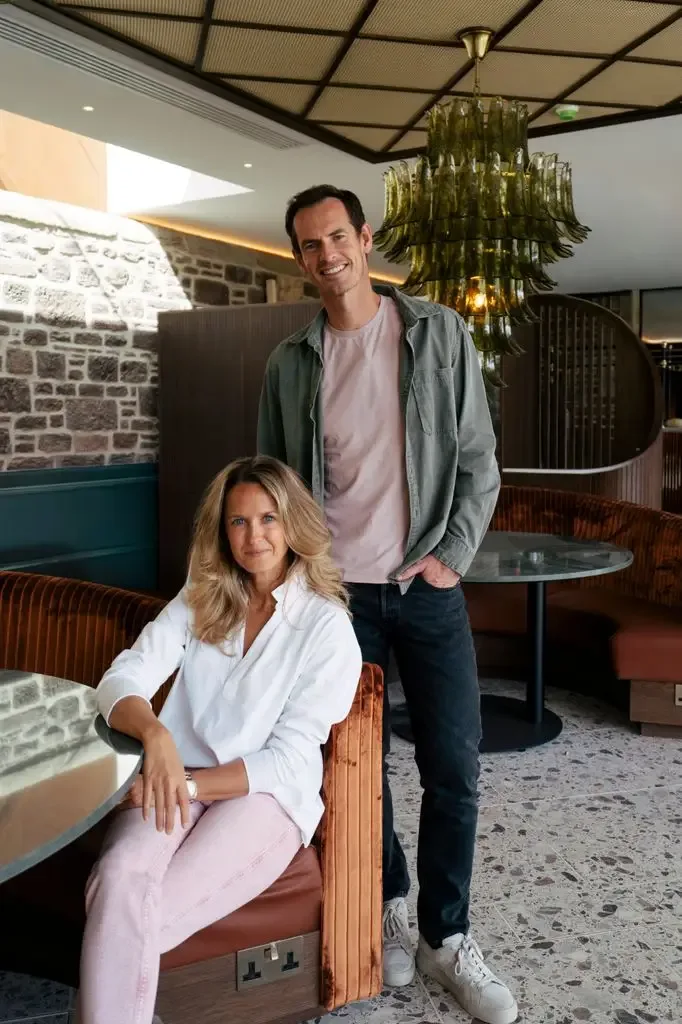 Andy Murray stands next to wife Kim in a lounge setting, both smiling.