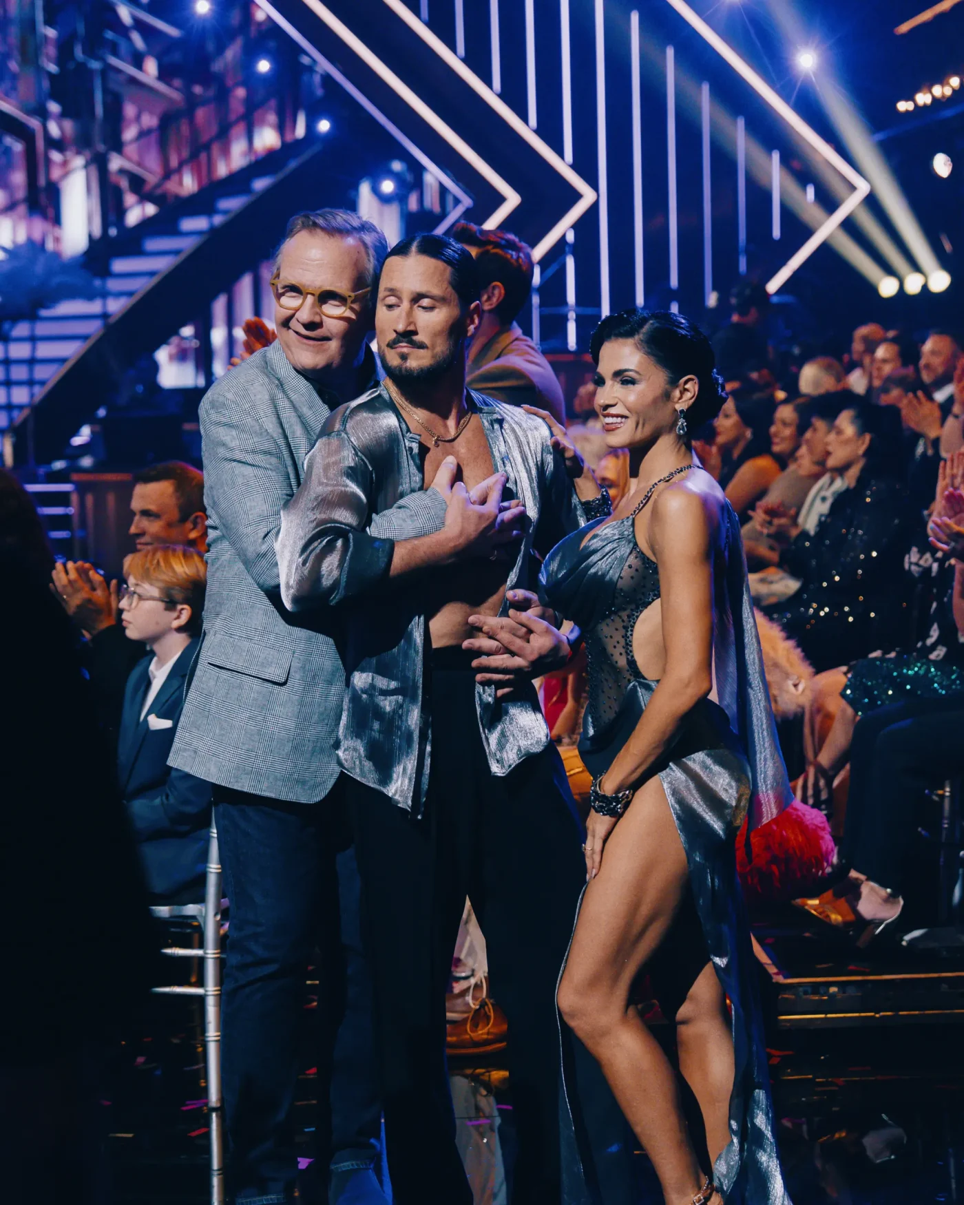 Andy Richter, Valentin Chmerkovskiy, and Jenna Dewan pose together in a ballroom setting.