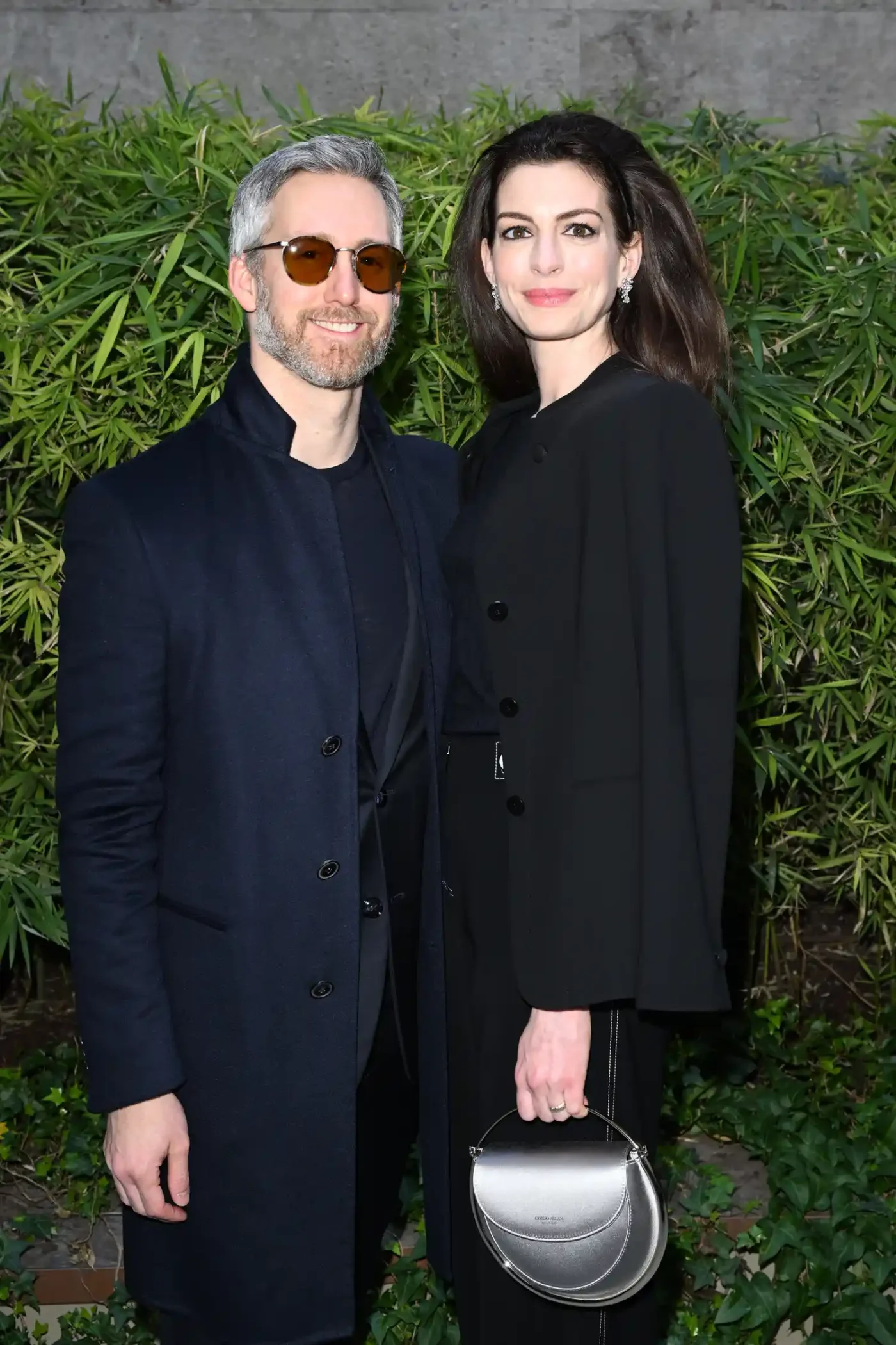 Anne Hathaway standing outdoors with another individual