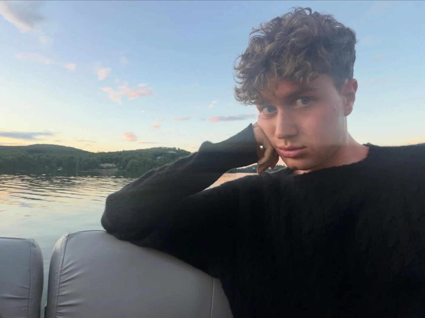 Ariel Ehrlich leaning on a boat seat outdoors with a lake and hills in the background.