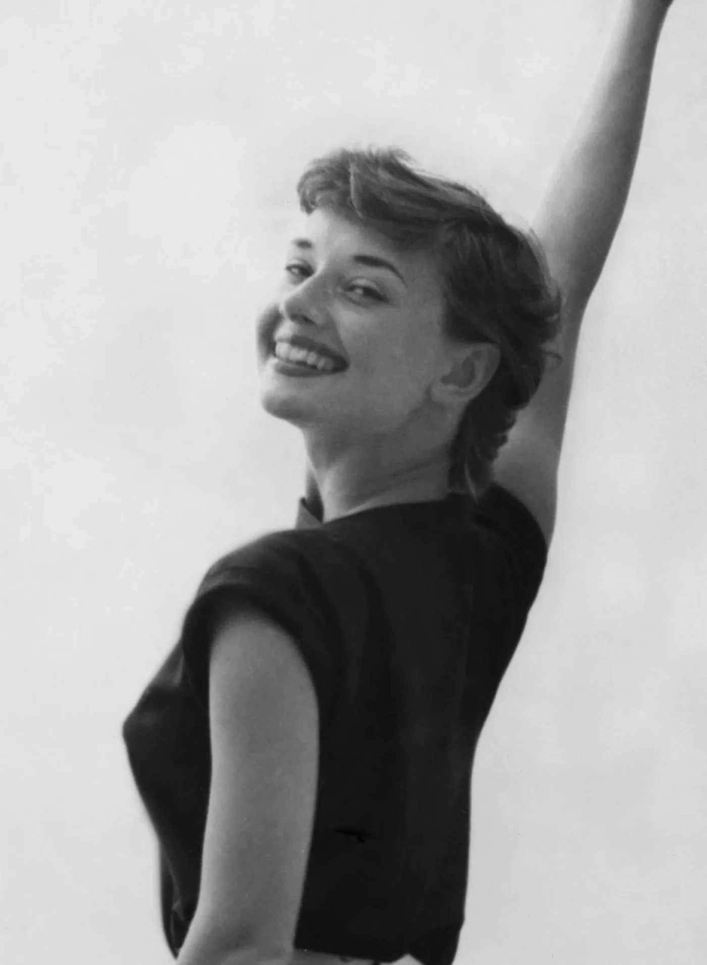 Audrey Hepburn smiling while raising one arm