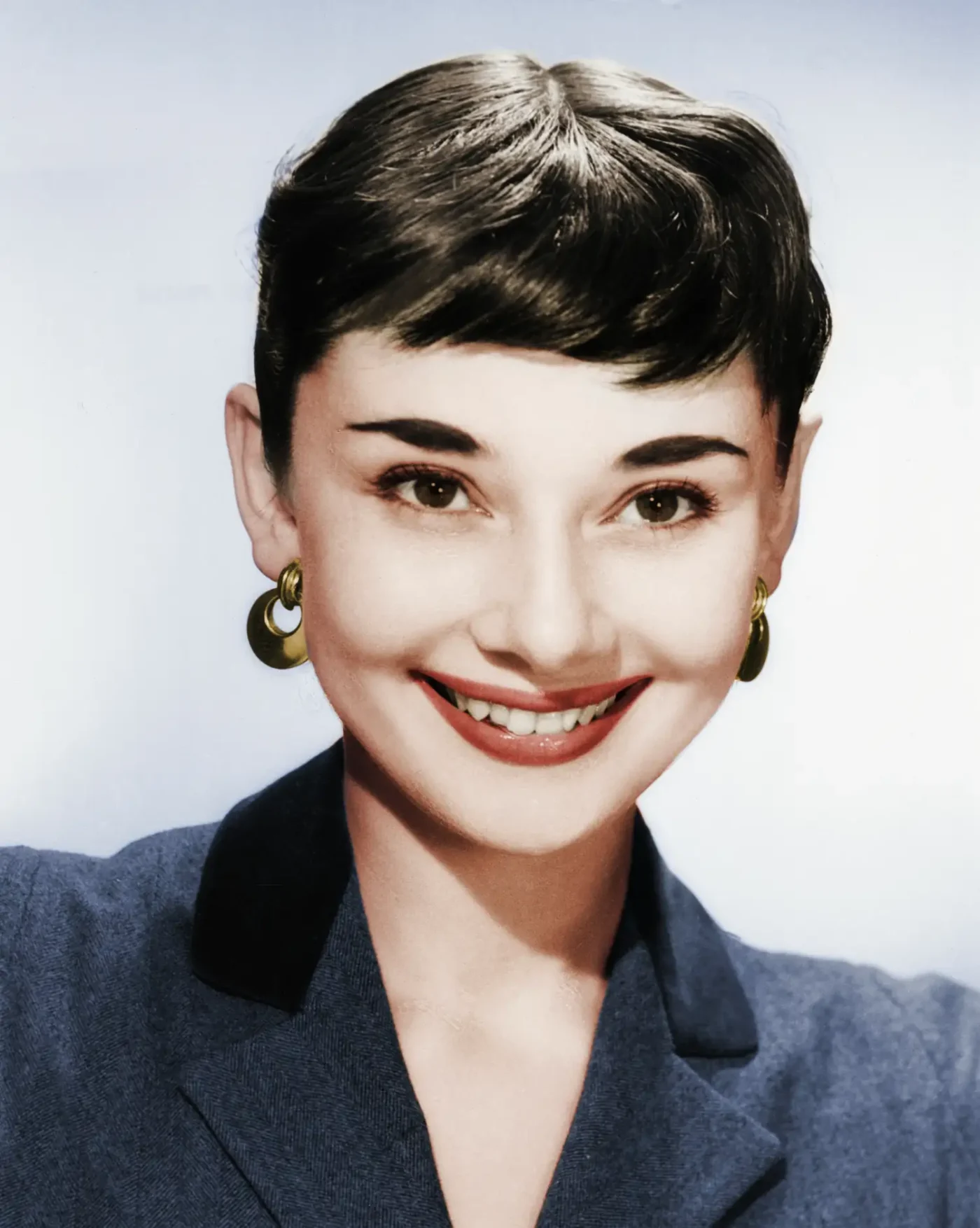 Audrey Hepburn wearing a navy blazer and her brunette hair in a pixie cut with microbangs