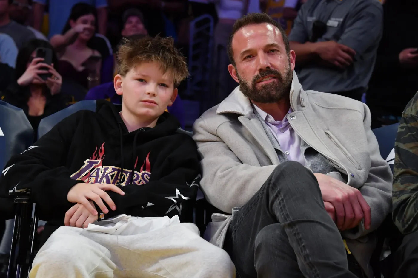 Ben Affleck sitting next to a young child at a sports event
