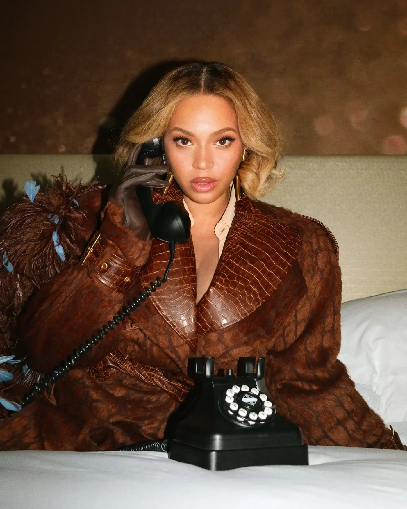 Beyonce posing in a brown coat while holding a vintage telephone in a hotel room.