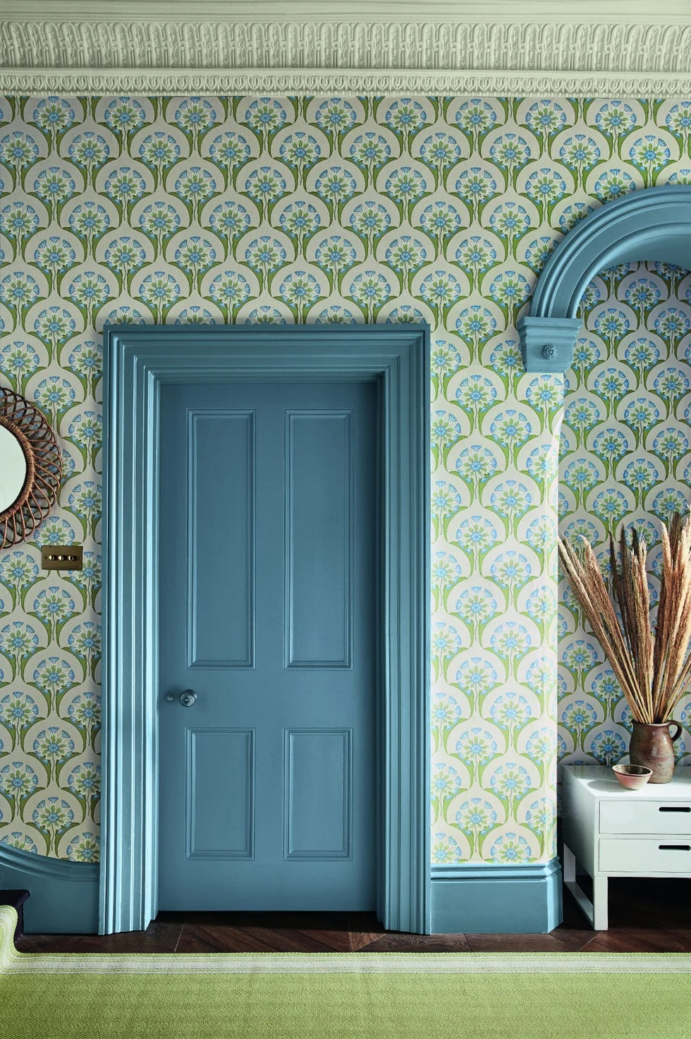 blue door with floral wallpaper and ornate blue trim in a vintage styled room.
