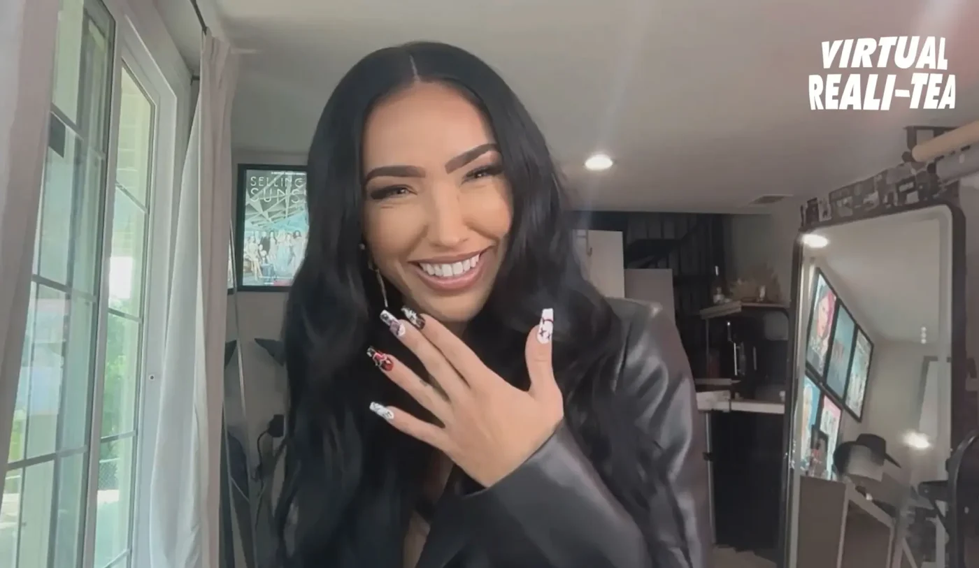 Bre Tiesi laughing while holding her hand to her chest.