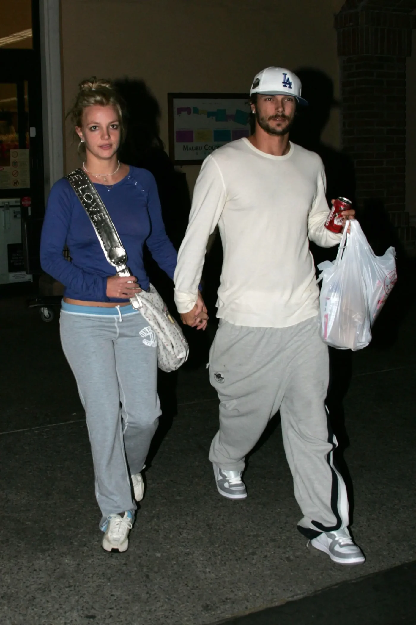Britney Spears and Kevin Federline walking together outside a store, holding hands and carrying grocery bags.