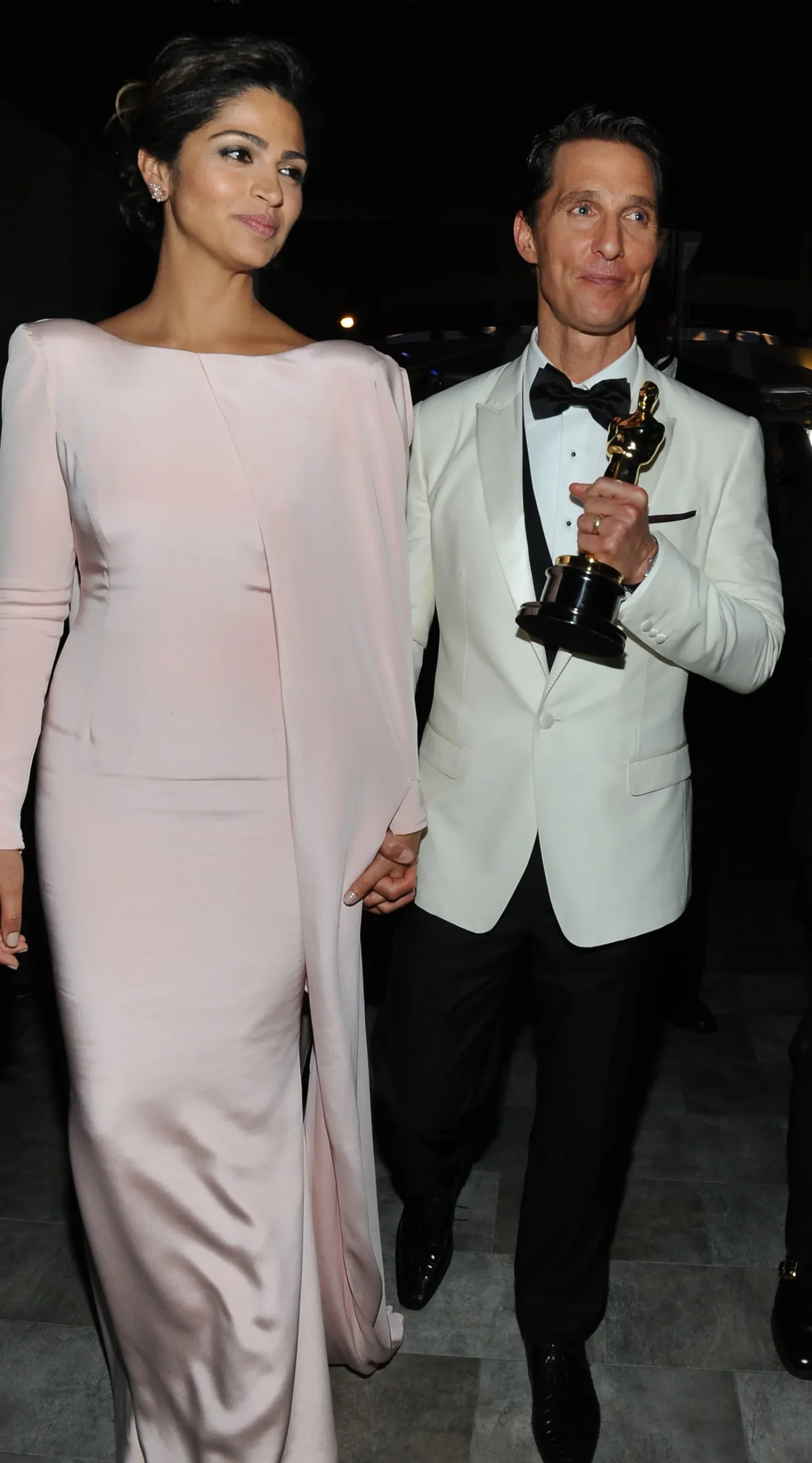 Camila Alves and Matthew McConaughey walking together McConaughey holding an award