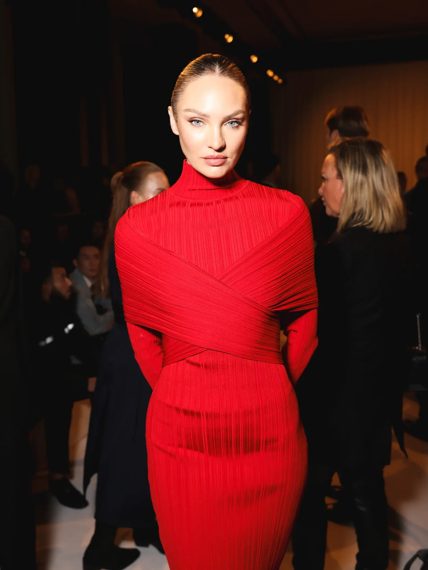 Candice Swanepoel wearing a red turtleneck dress at the Balmain show during Paris Fashion Week.