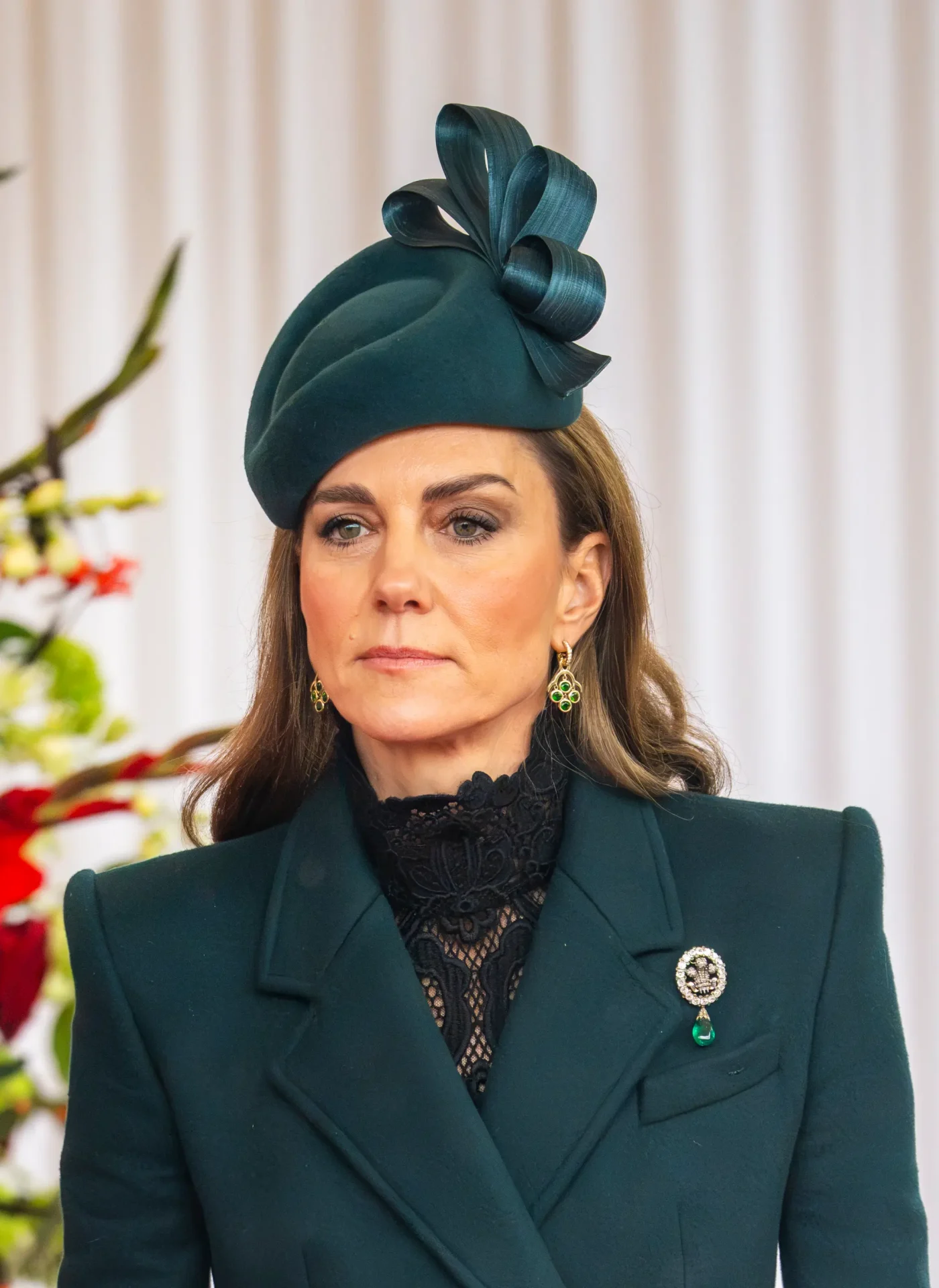 Catherine, Princess of Wales, wearing a dark green coat, matching hat, and brooch at the welcome ceremony for the Sultan of Oman in Windsor.
