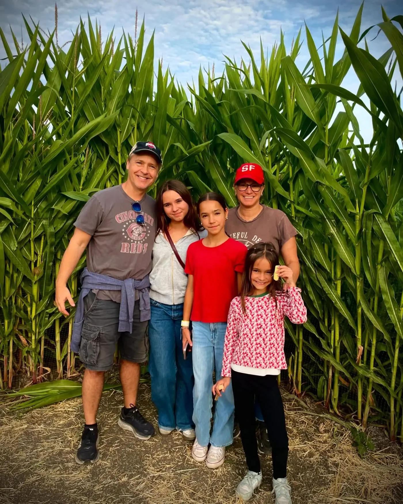 Chad Lowe and his family, wife Kim, and daughters Mabel, Fiona, and Nixie, pose in front of a tall cornstalk maze.