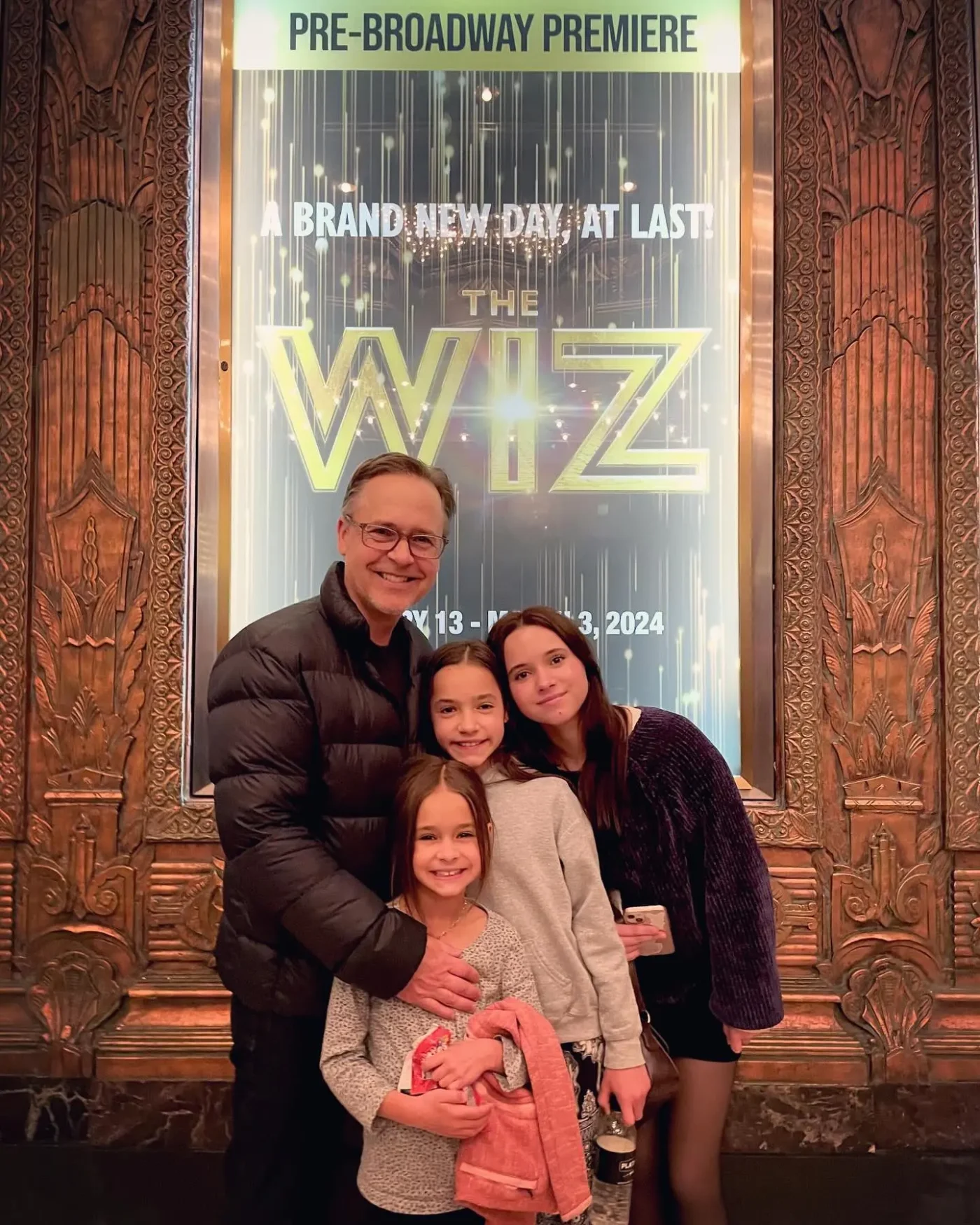 Chad Lowe poses with his daughters Mabel, Fiona, and Nixie in front of a poster for