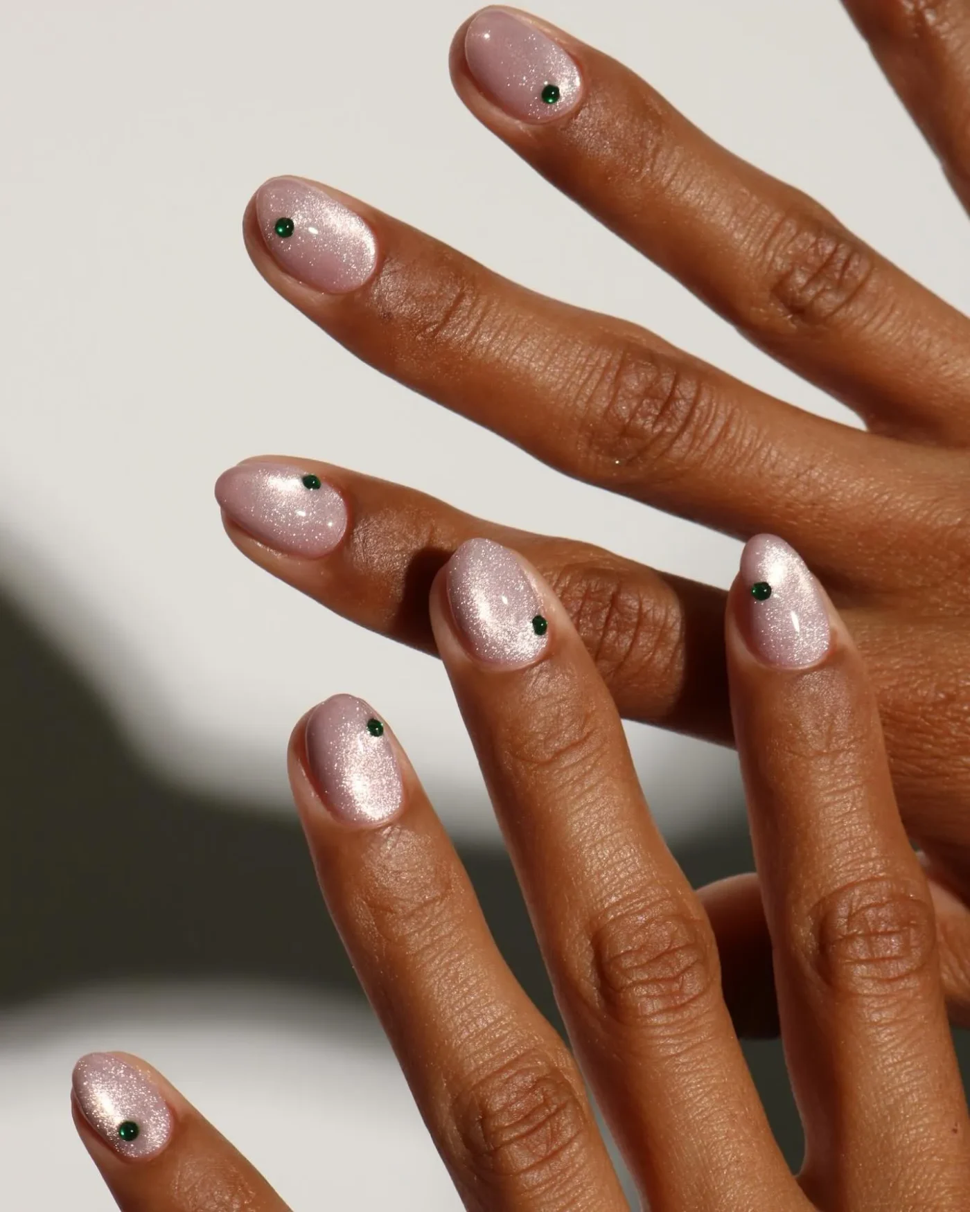 Champagne cat-eye nails with an emerald gem accent on each nail