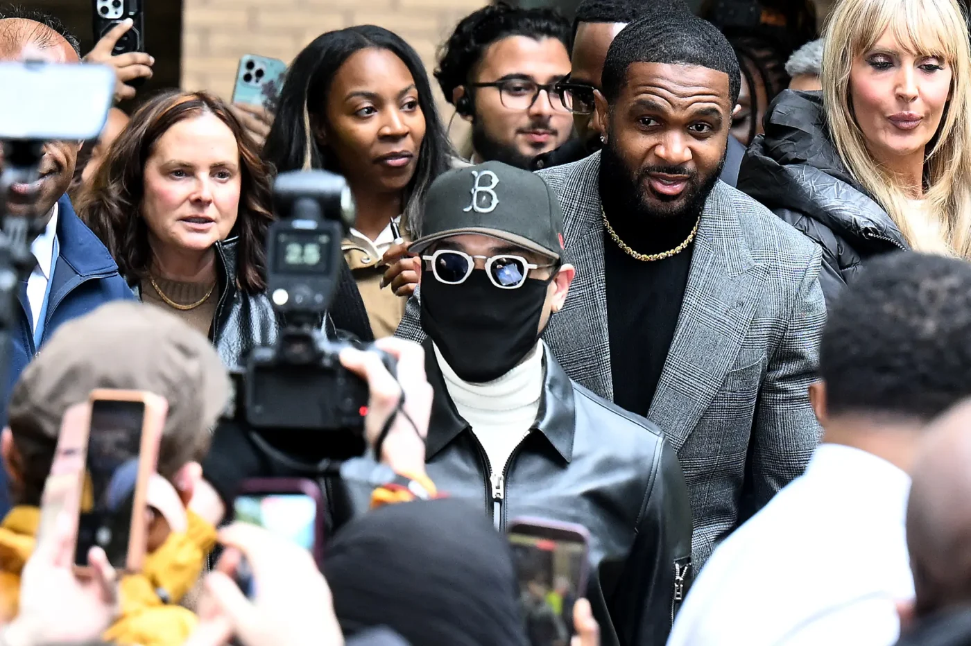 Chris Brown leaves court surrounded by media and onlookers.