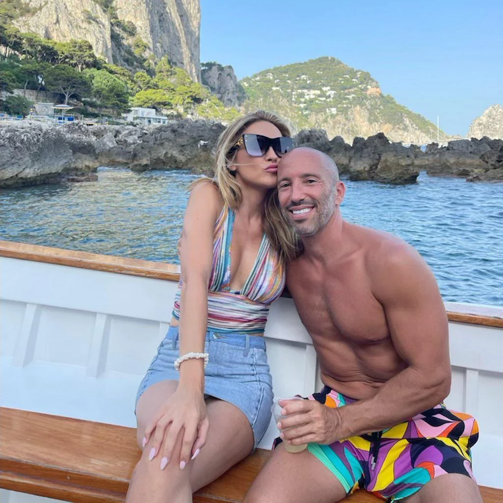 Chrishell Stause and Jason Oppenheim on a boat in front of rocky cliffs.