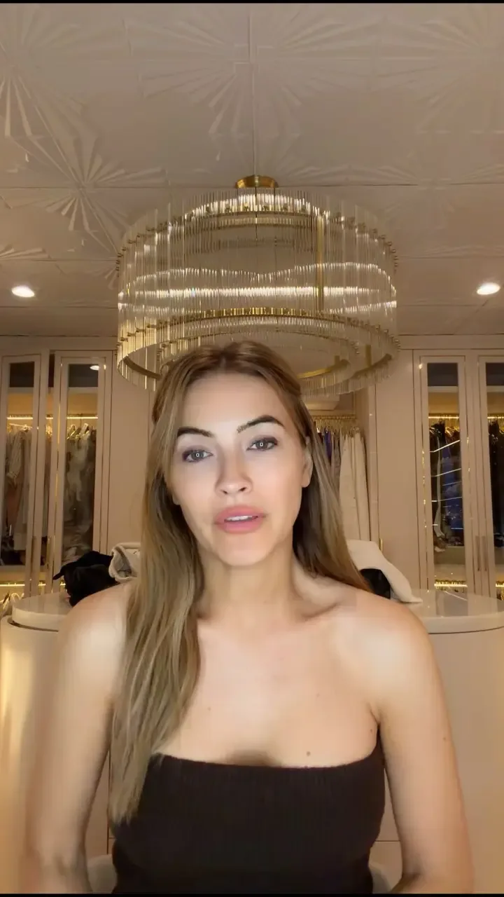 Chrishell Stause standing in a room with a decorative ceiling and a chandelier.