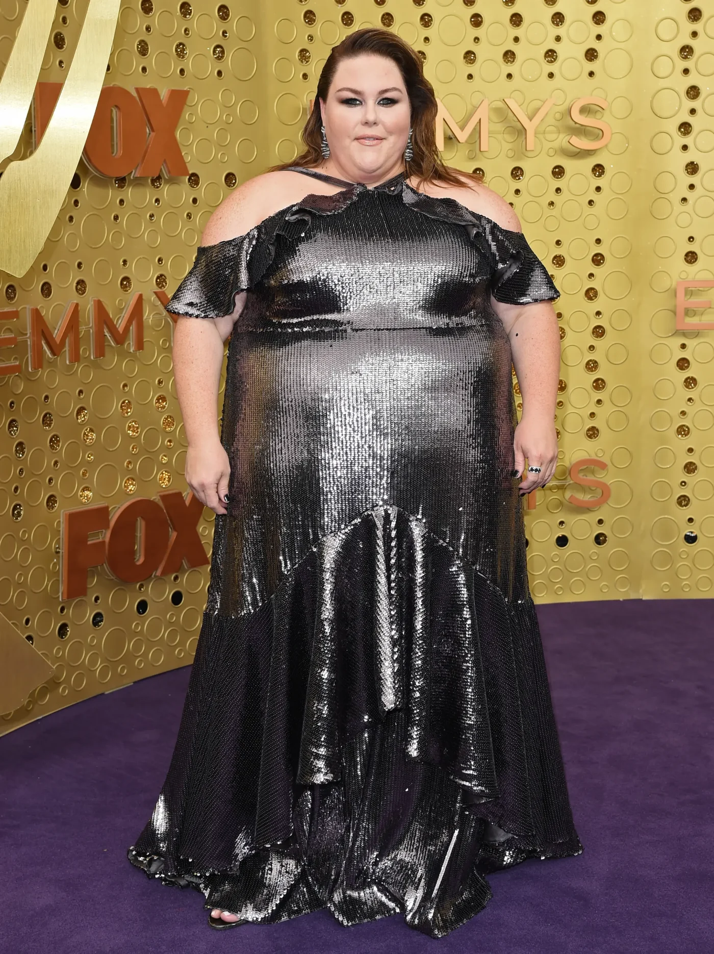 Chrissy Metz wears a silver sequined, cold-shoulder gown on the red carpet at the Emmy Awards.