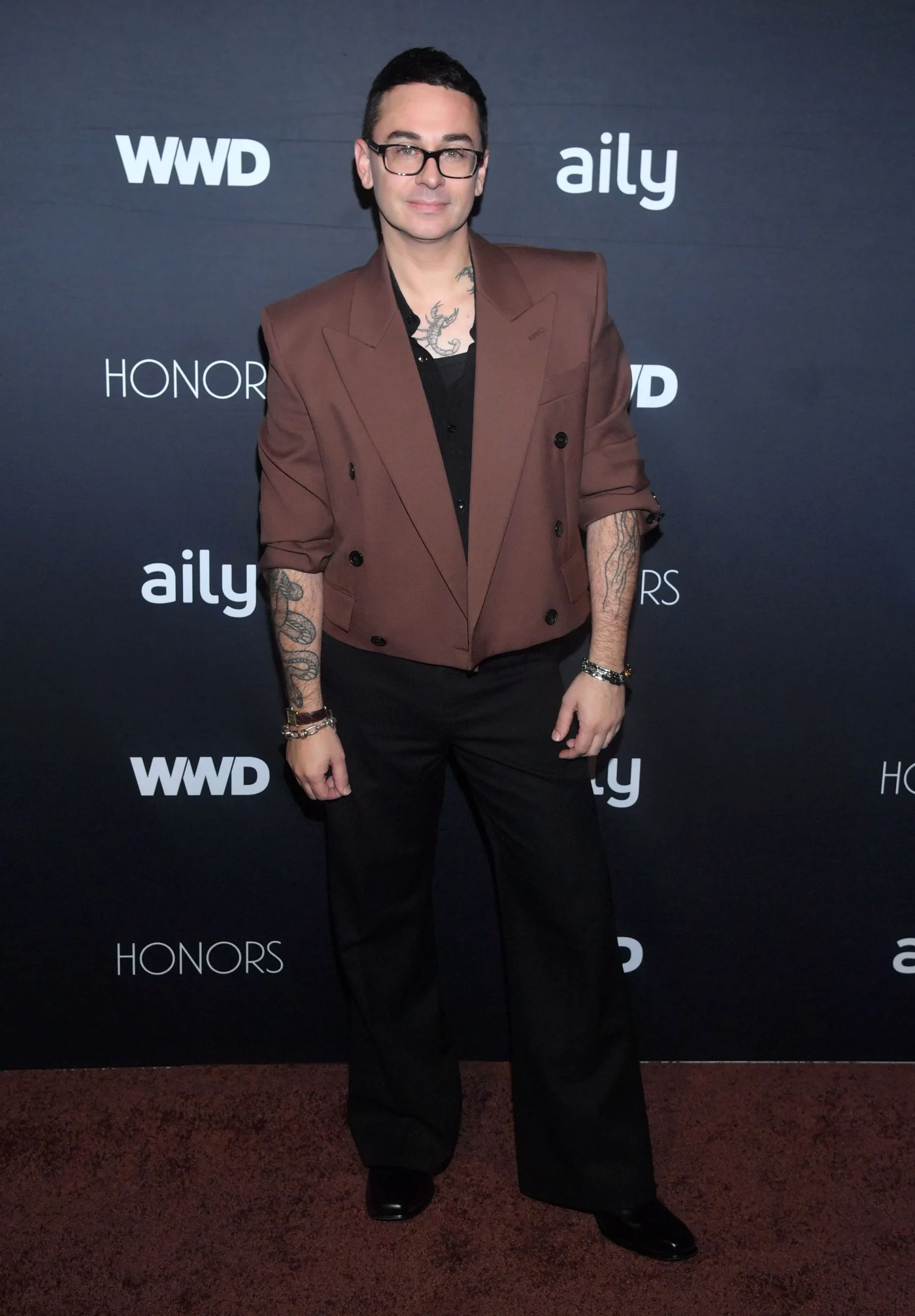 Christian Siriano wearing a brown double-breasted cropped blazer and black trousers at the 2026 WWD Honors.
