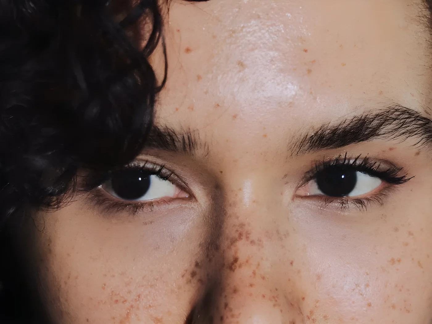 Closeup view of a persons eyes with curly hair partially visible