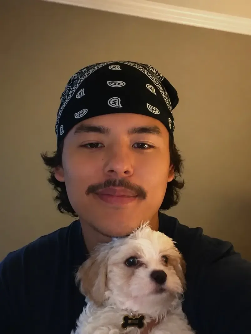 Collin Gosselin wearing a black bandana while holding a small fluffy puppy.