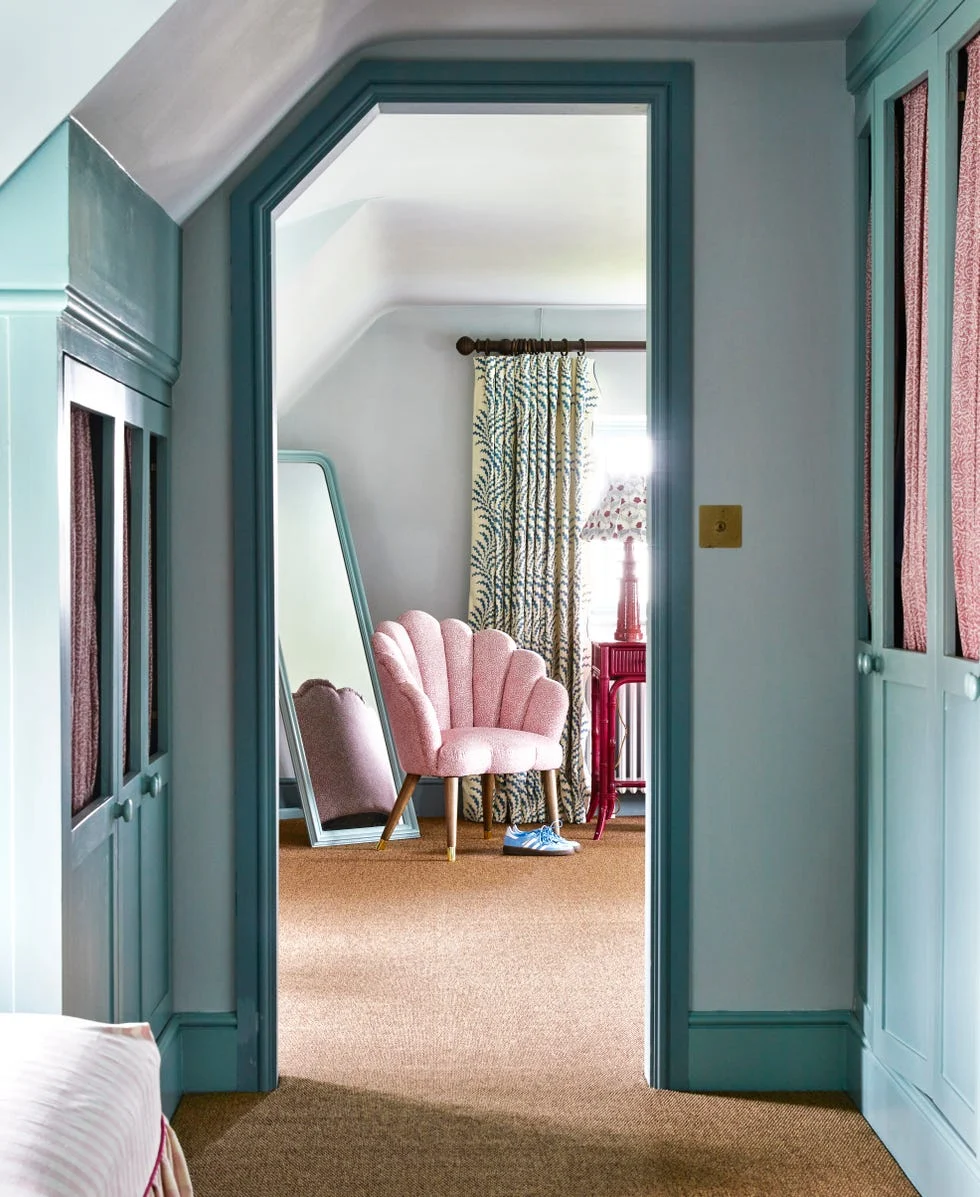 cozy room with pink chair, large mirror, and patterned curtains.