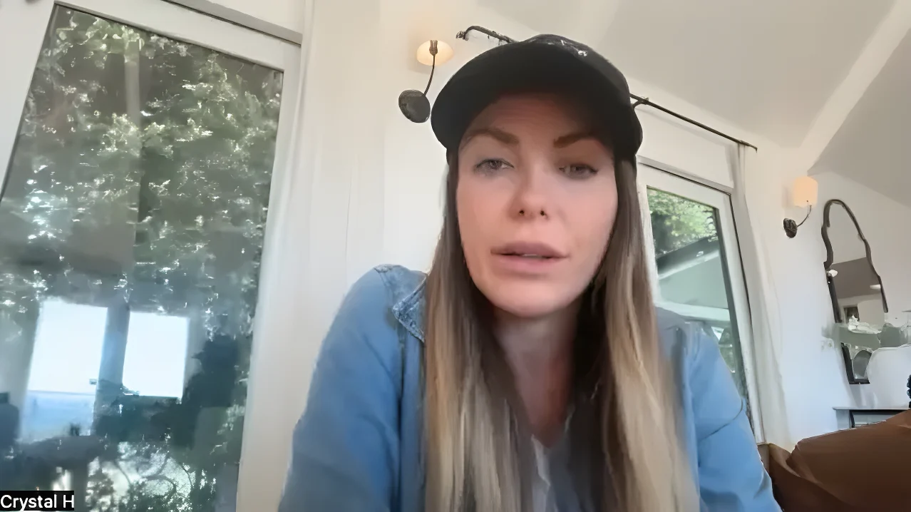 Crystal Hefner in a video call, wearing a black cap and a denim shirt.
