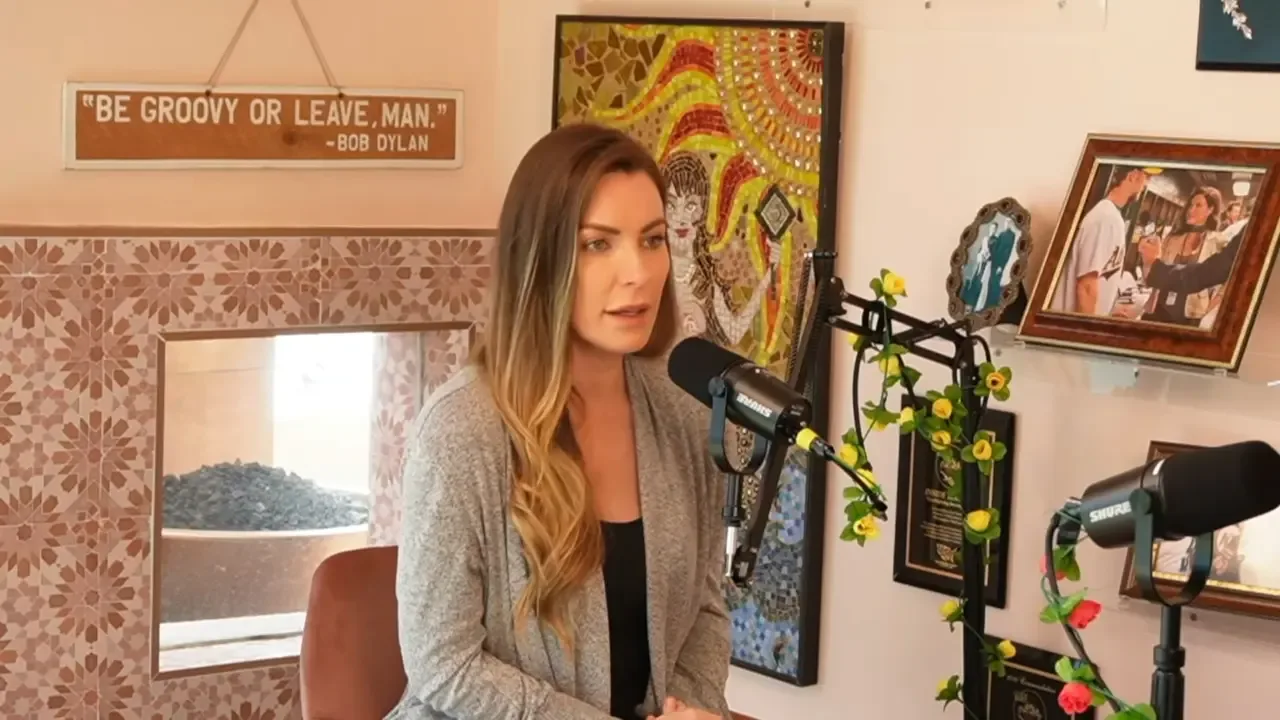 Crystal Hefner sitting in front of a microphone and speaking during an interview.
