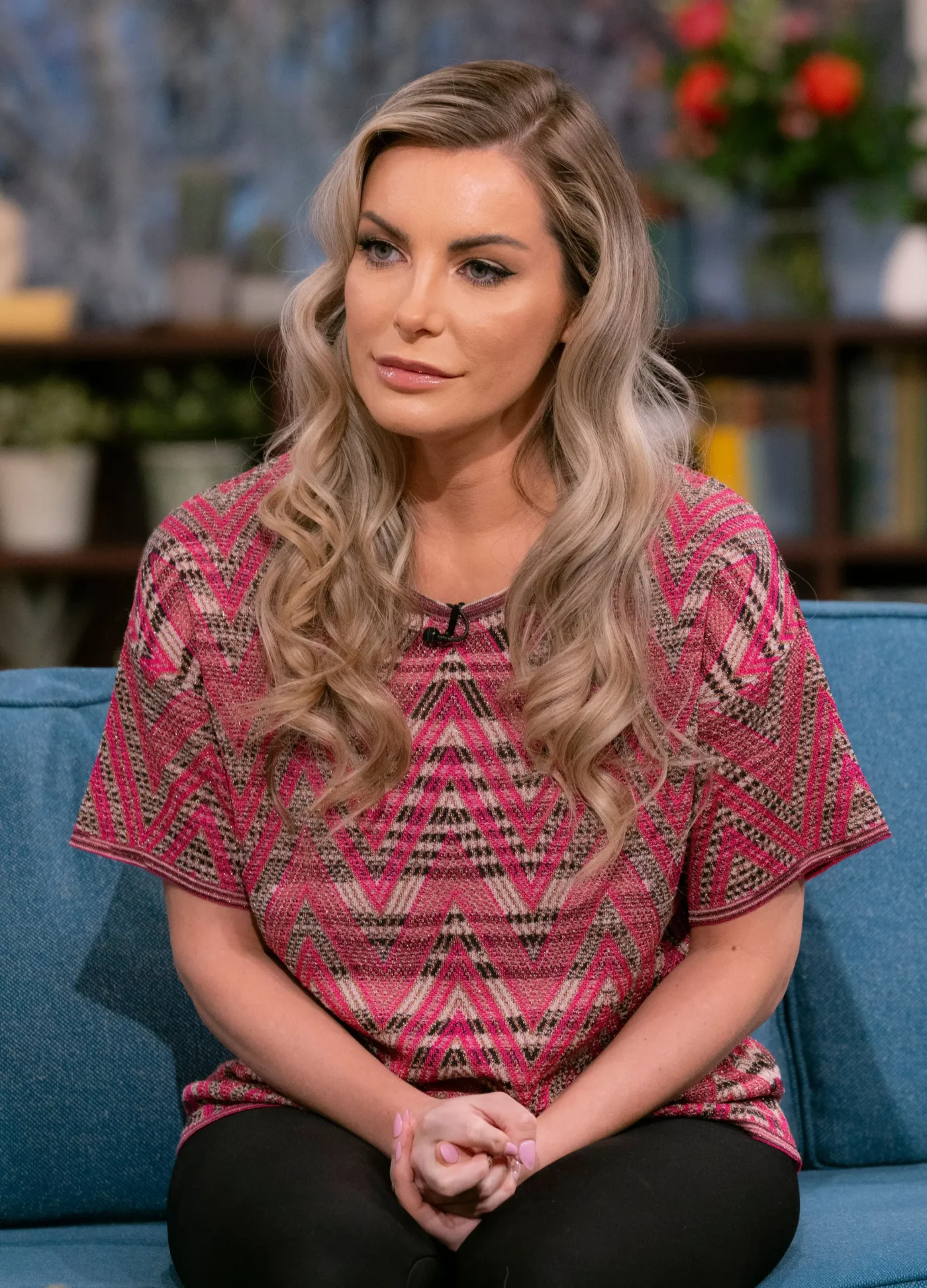 Crystal Hefner sitting on a blue sofa on the set of