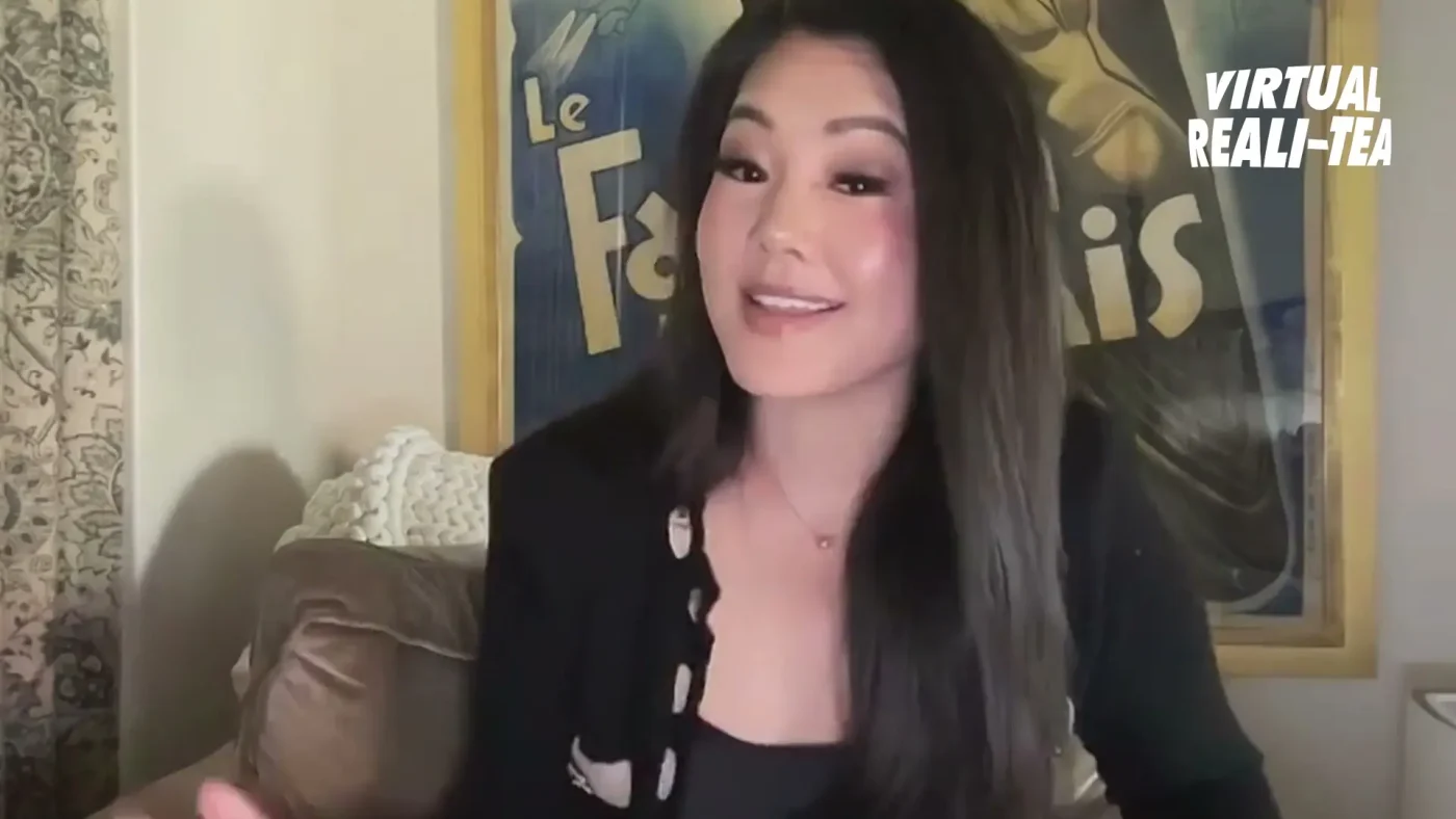 Crystal Kung Minkoff sitting on a couch with a poster behind her.